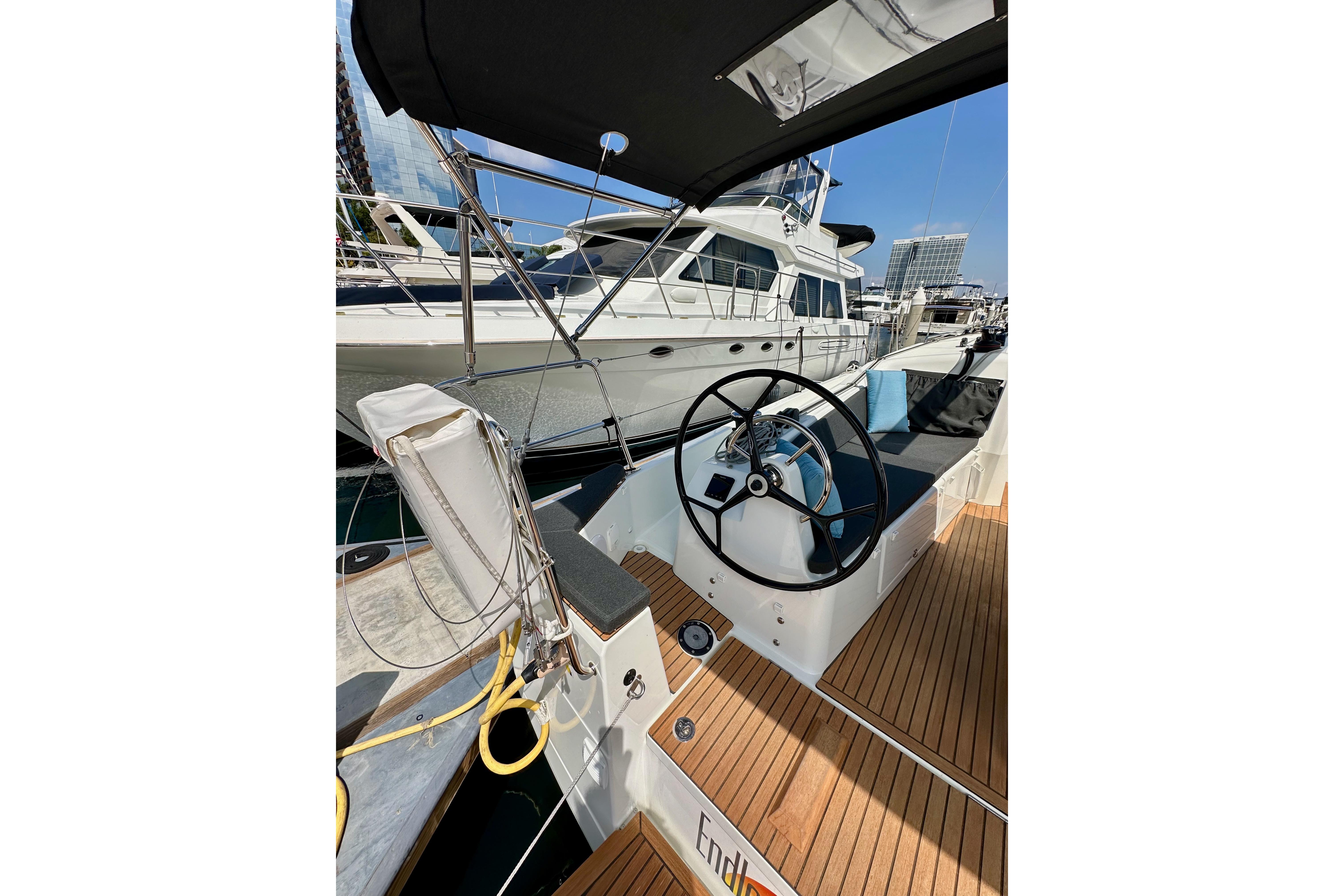 2024 Jeanneau Sun Odyssey 410 sailboat cockpit with steering wheel, docked at marina.