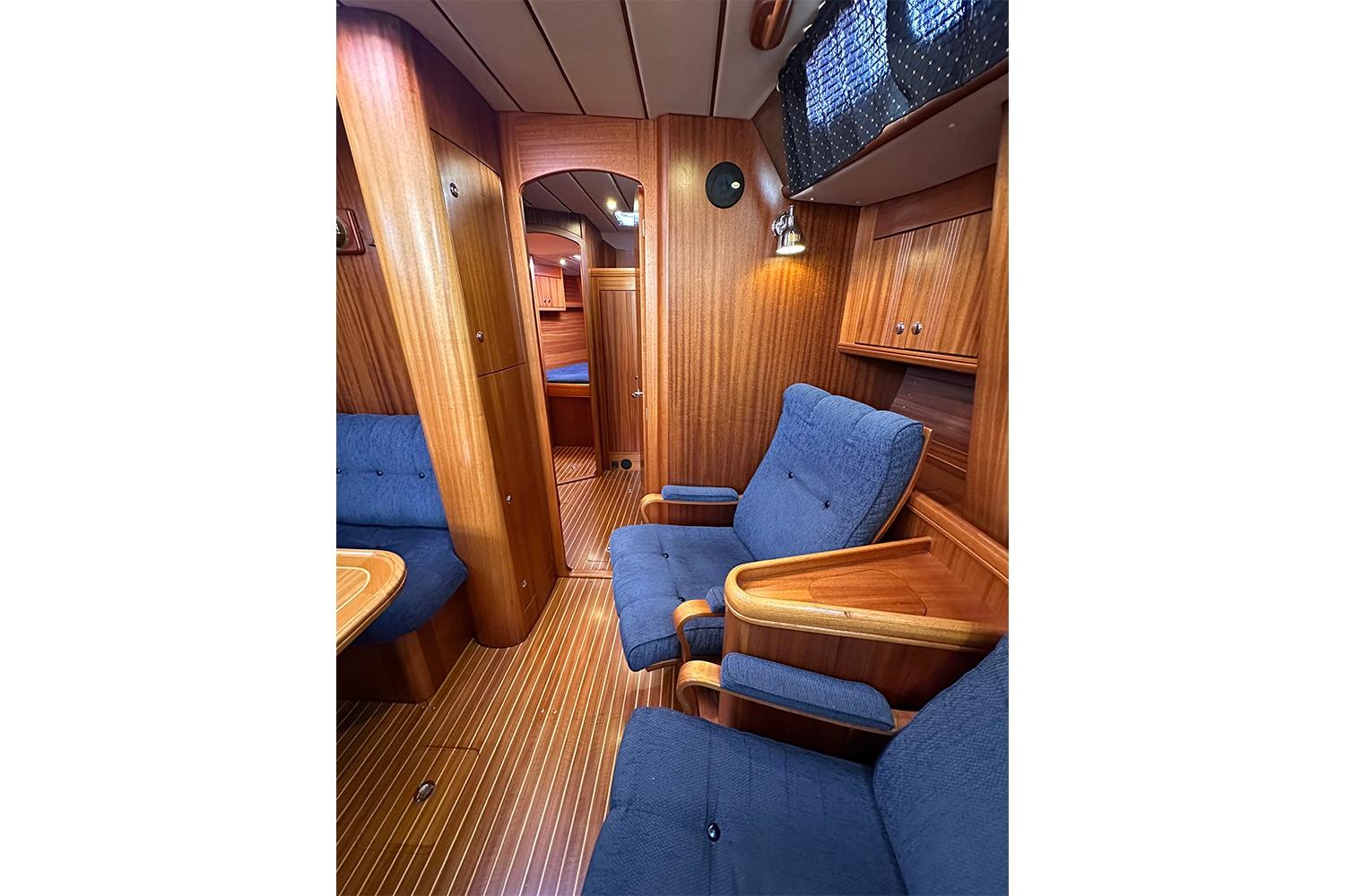 Luxurious 2004 Najad 460 yacht interior with wooden paneling and blue upholstered seating.