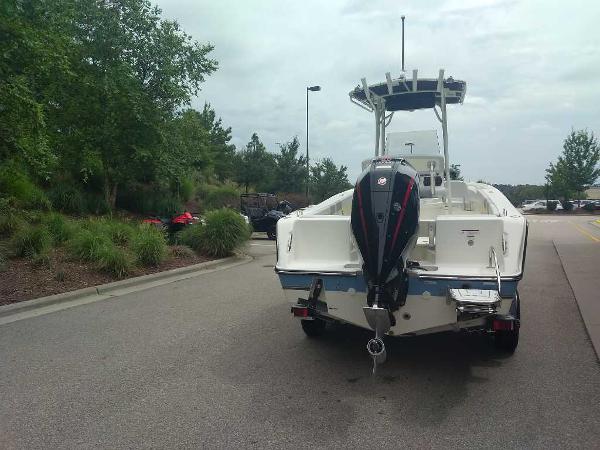 2023 Mako 214 CC boat with outboard motor parked on a road near greenery.