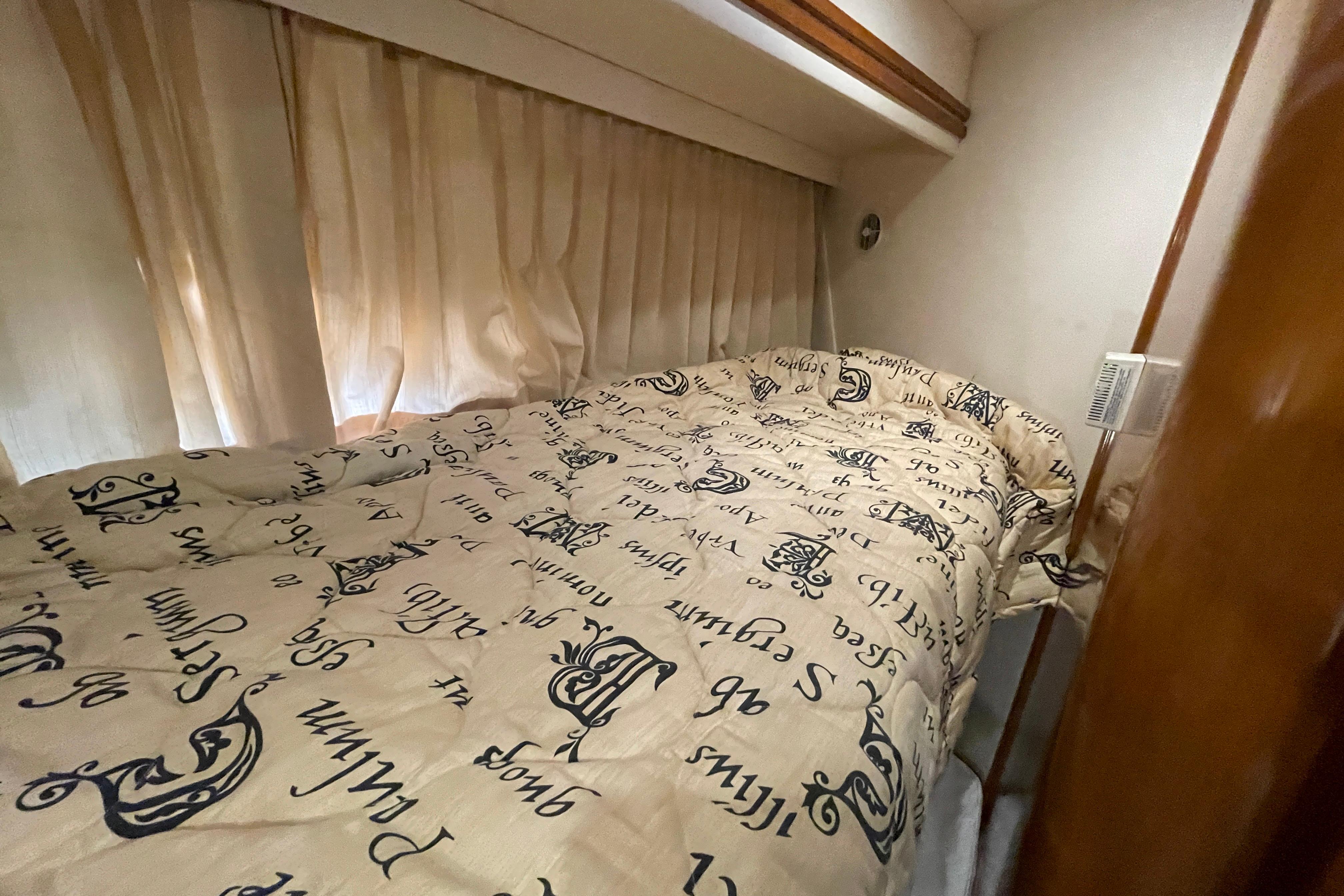 Cozy bedroom in 2002 Carver 570 Voyager Pilothouse with patterned bedding and curtains.