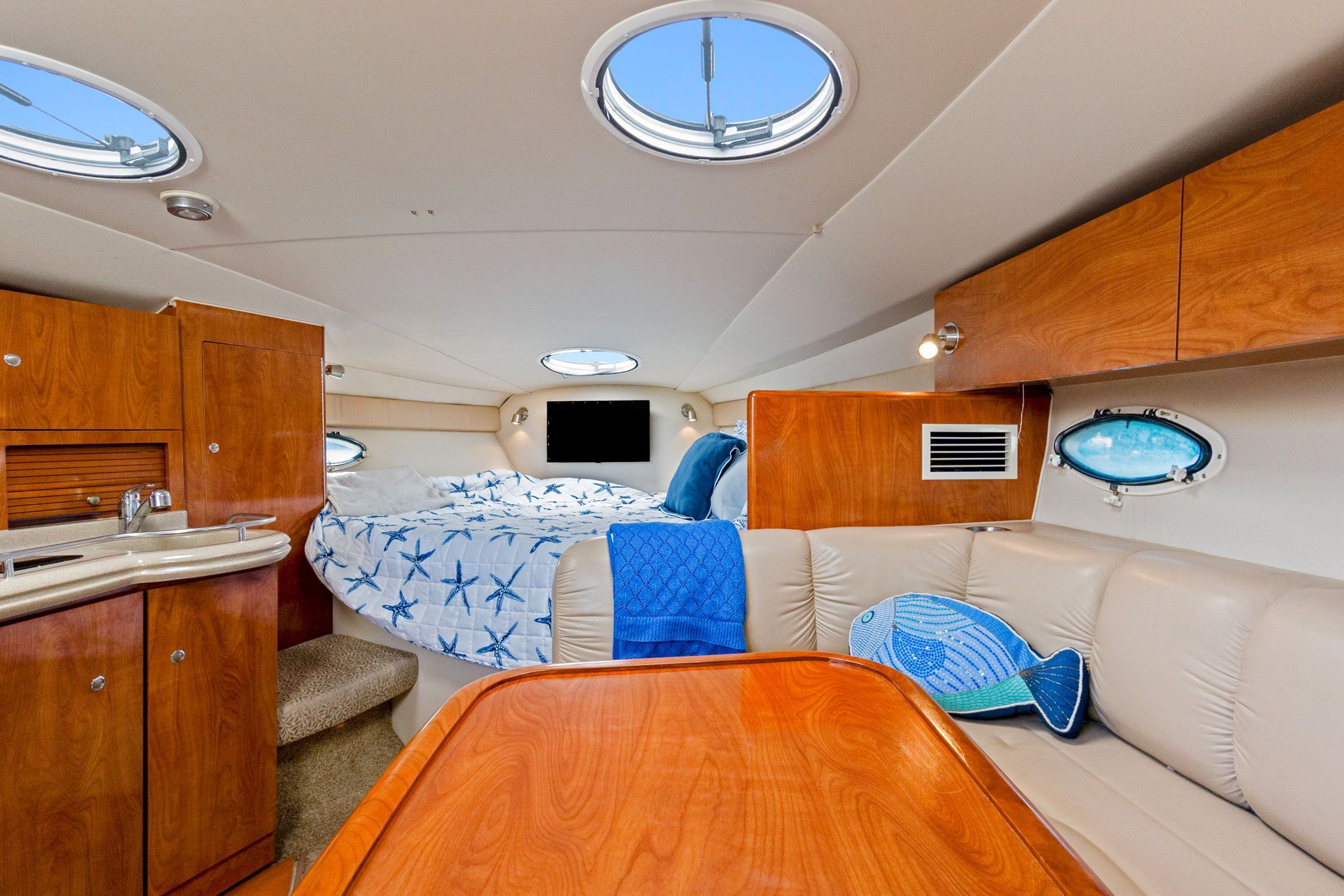 Interior of a 2007 Larson Cabrio 330 with wooden furnishings and a cozy sleeping area.
