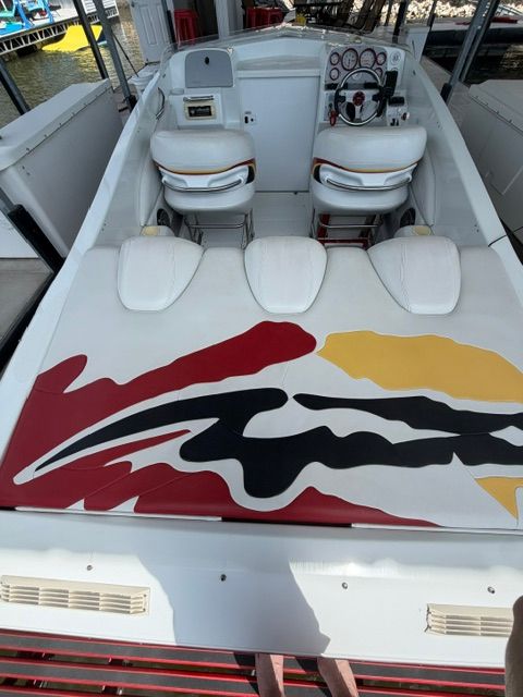 The image shows a 2002 Baja 25 Outlaw boat with colorful design on the deck.