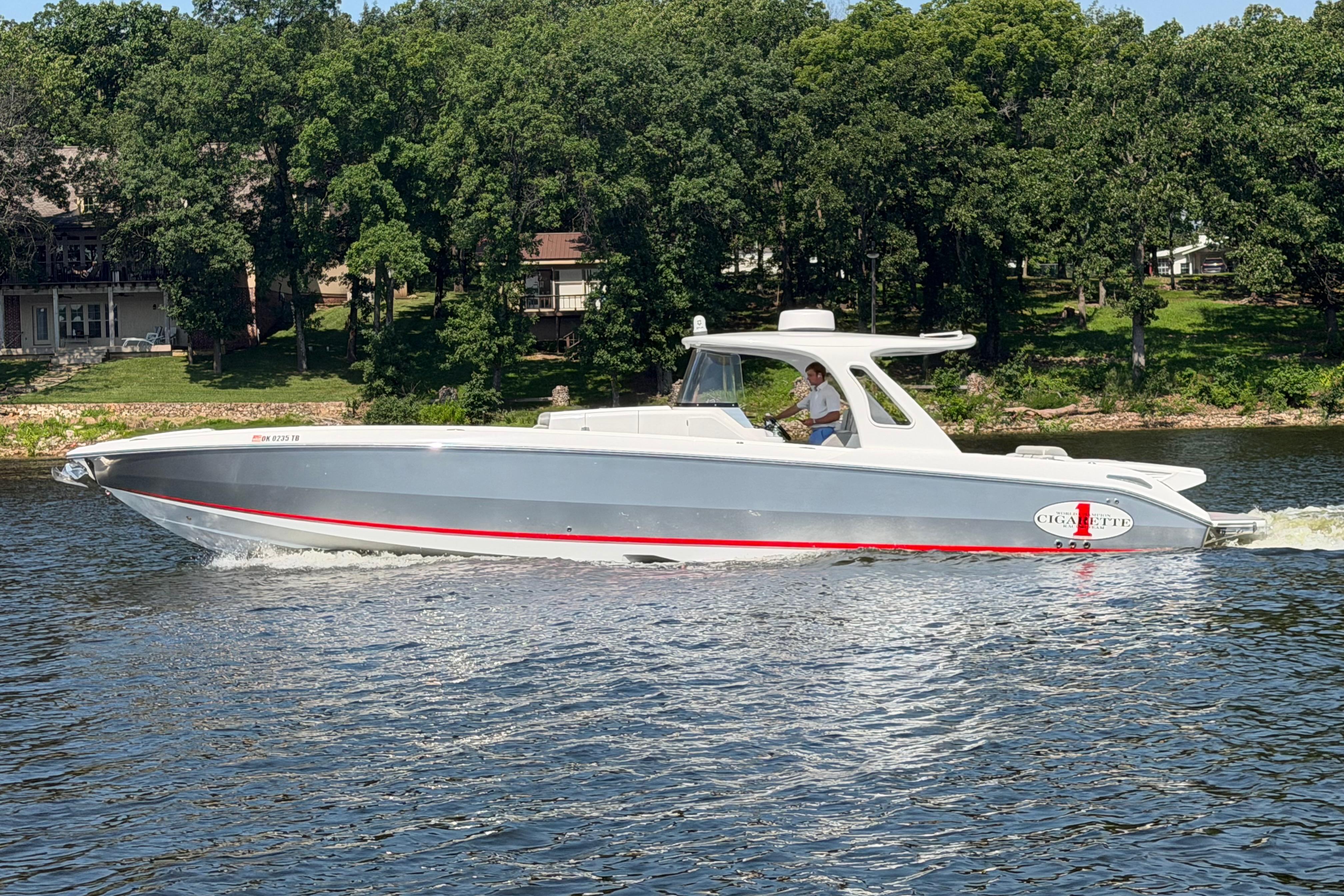 2015 Cigarette 41' Nighthawk SD Edition boat cruising on a lake with lush green backdrop.