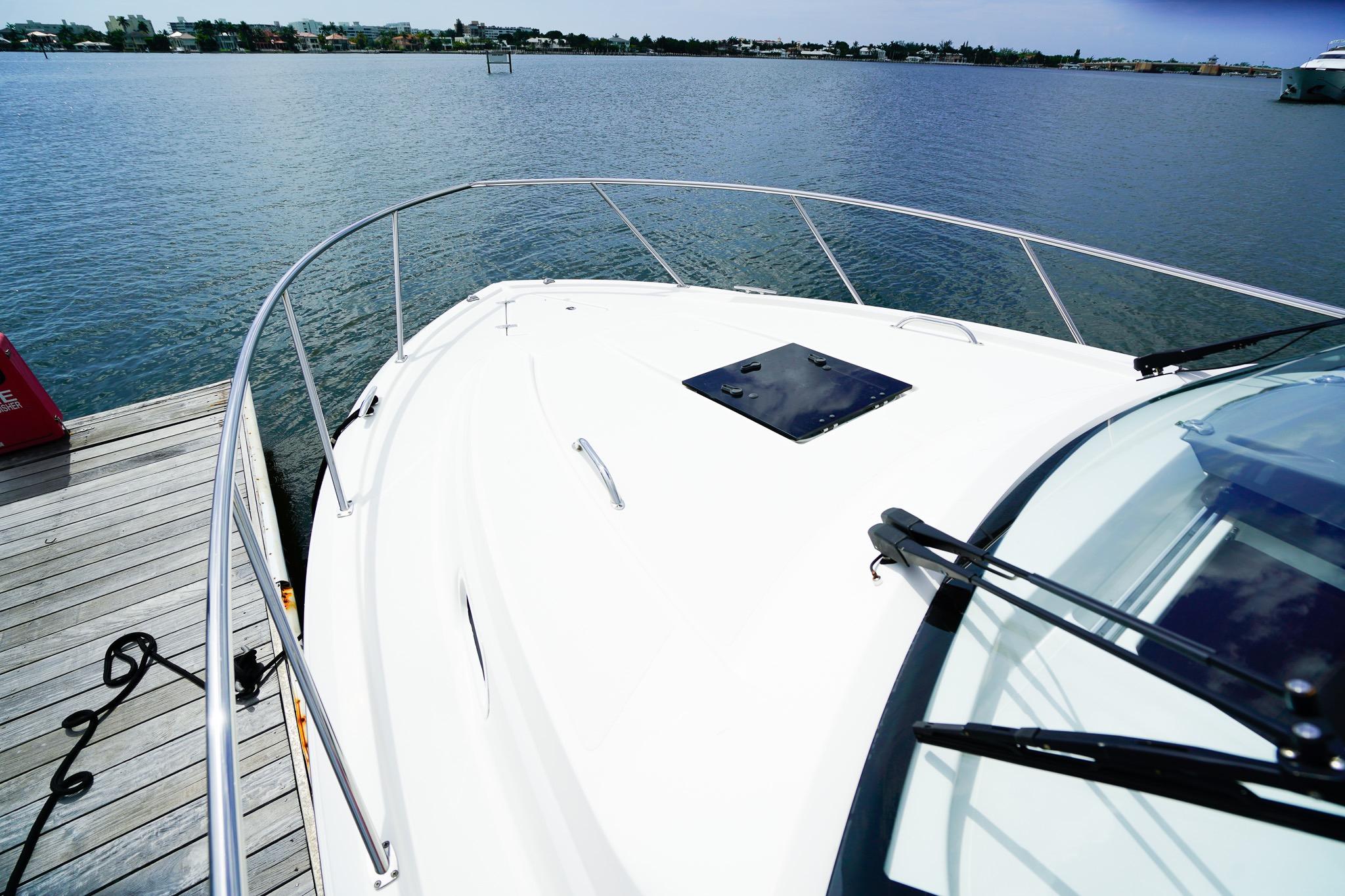 2020 Pursuit OS 325 Offshore boat docked by the water, showcasing sleek design and railing.