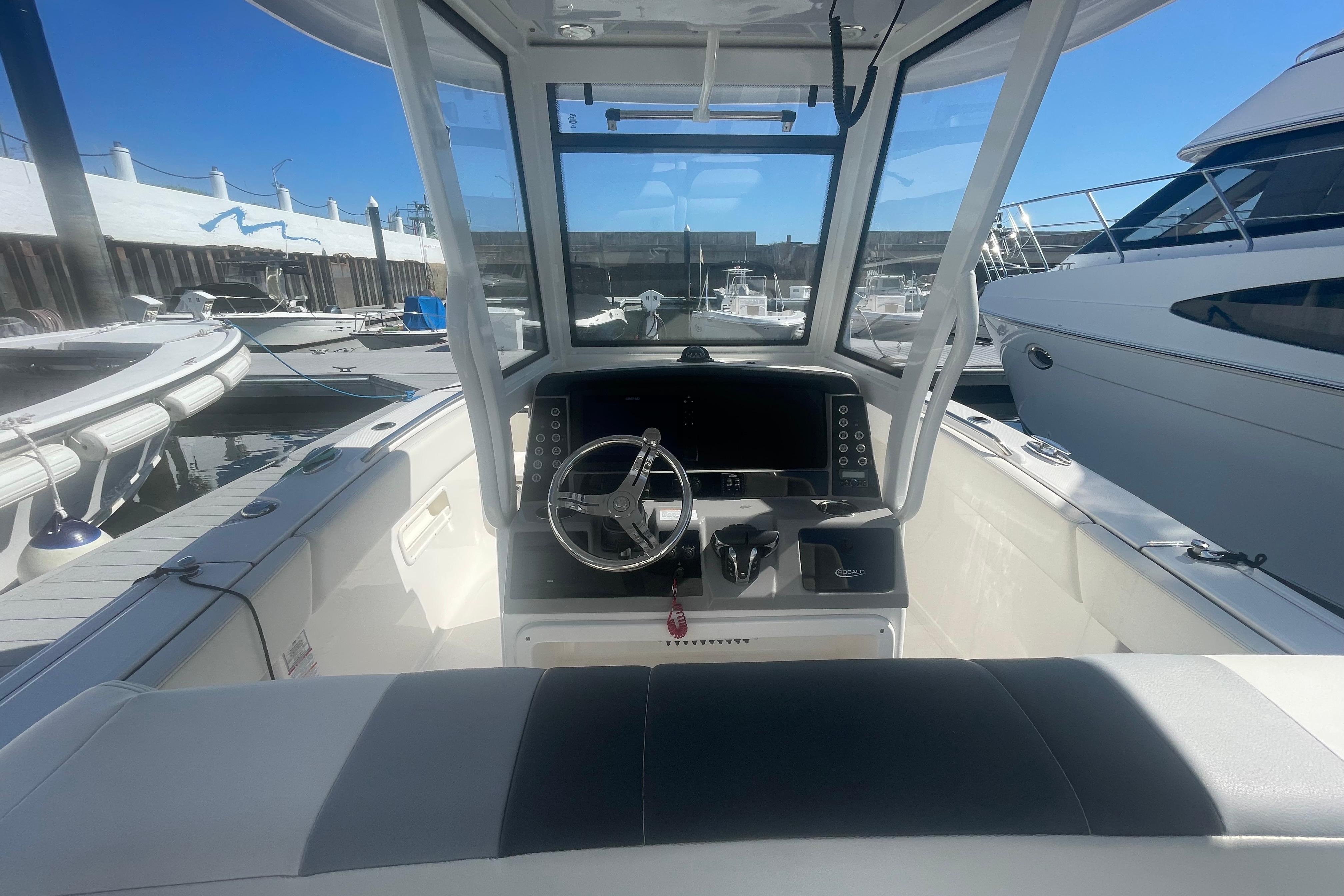 2023 Robalo R270 Center Console boat interior at marina, featuring steering wheel and dashboard.