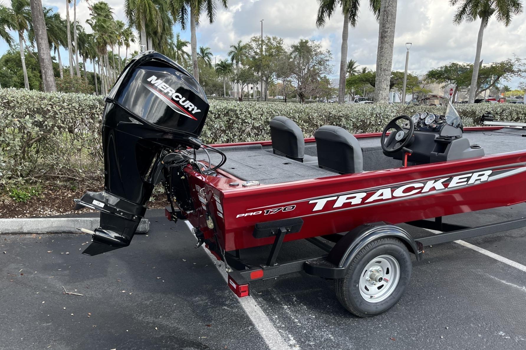2026 Tracker Pro 170 boat with Mercury engine, parked outdoors under palm trees.