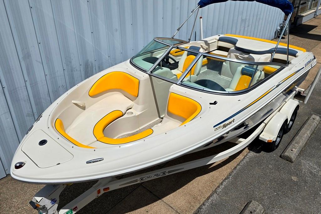 2007 Sea Ray 205 Sport boat with yellow seating, on a trailer, parked by a metal building.