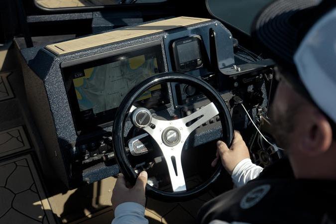 Person steering 2026 SeaArk Dynasty 2.0 boat with navigation display.