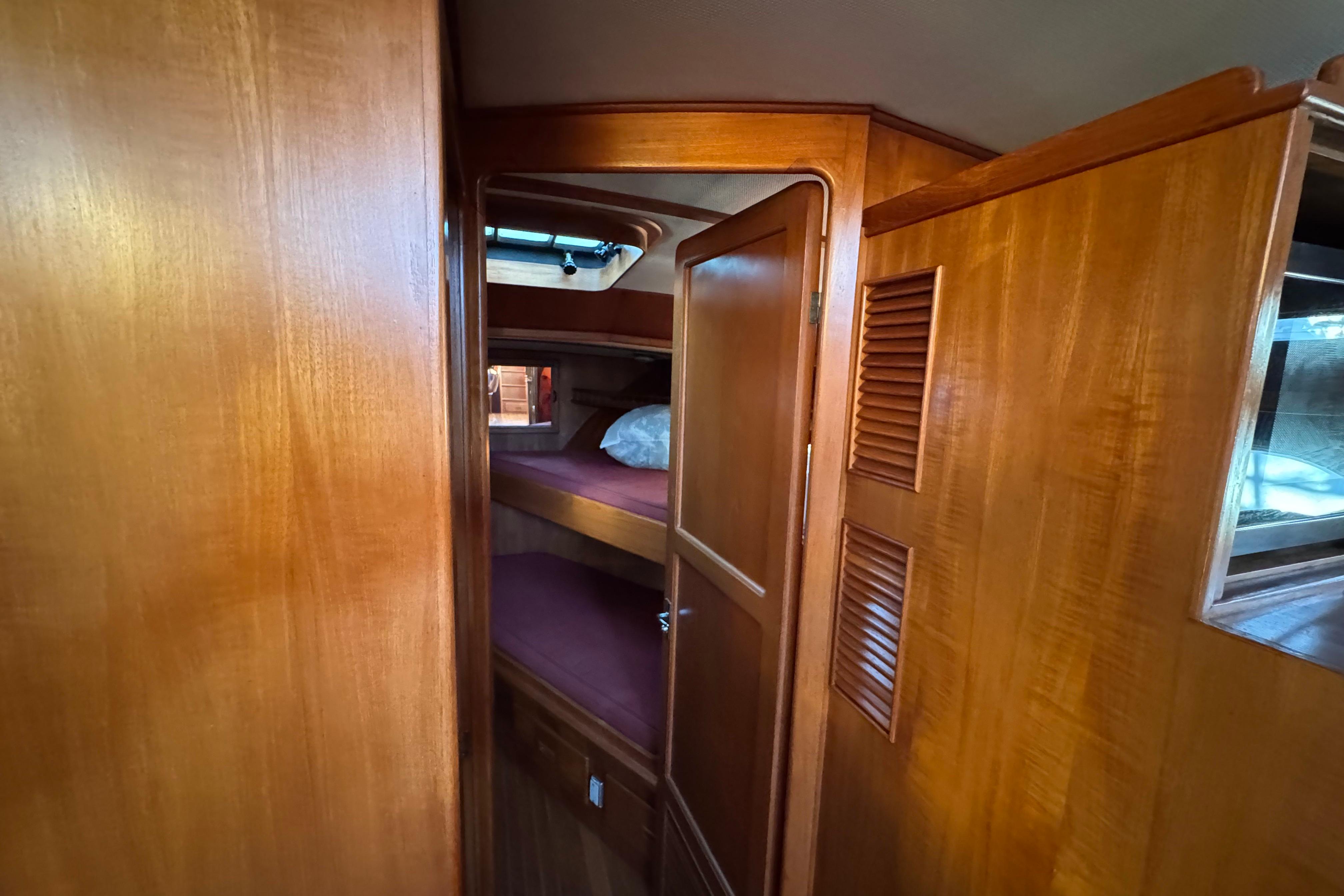 Wood-paneled cabin interior of a 1987 President 37 yacht, featuring cozy bunk beds.