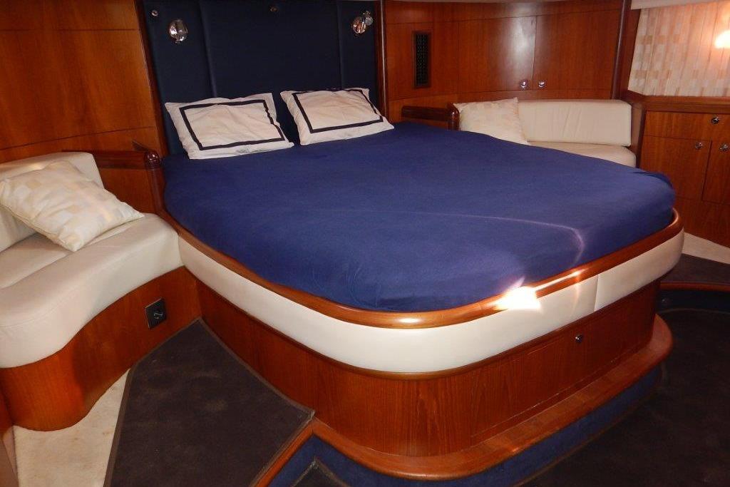 Luxurious cabin interior of a 2004 Moody 56 yacht with a cozy bed and elegant wood finish.