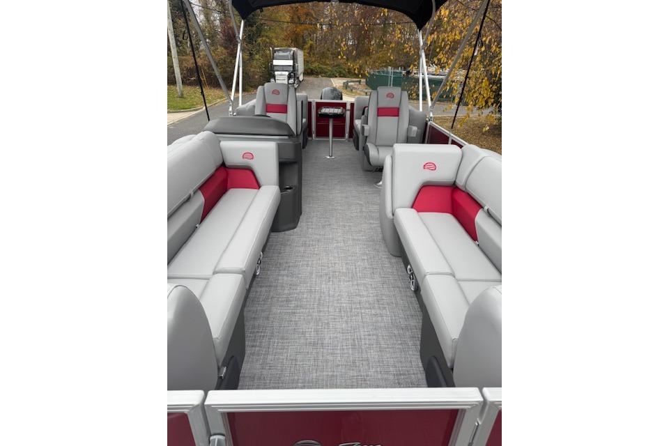2026 Sun Tracker Party Barge 22 DLX interior with gray and red seating, outdoor setting.