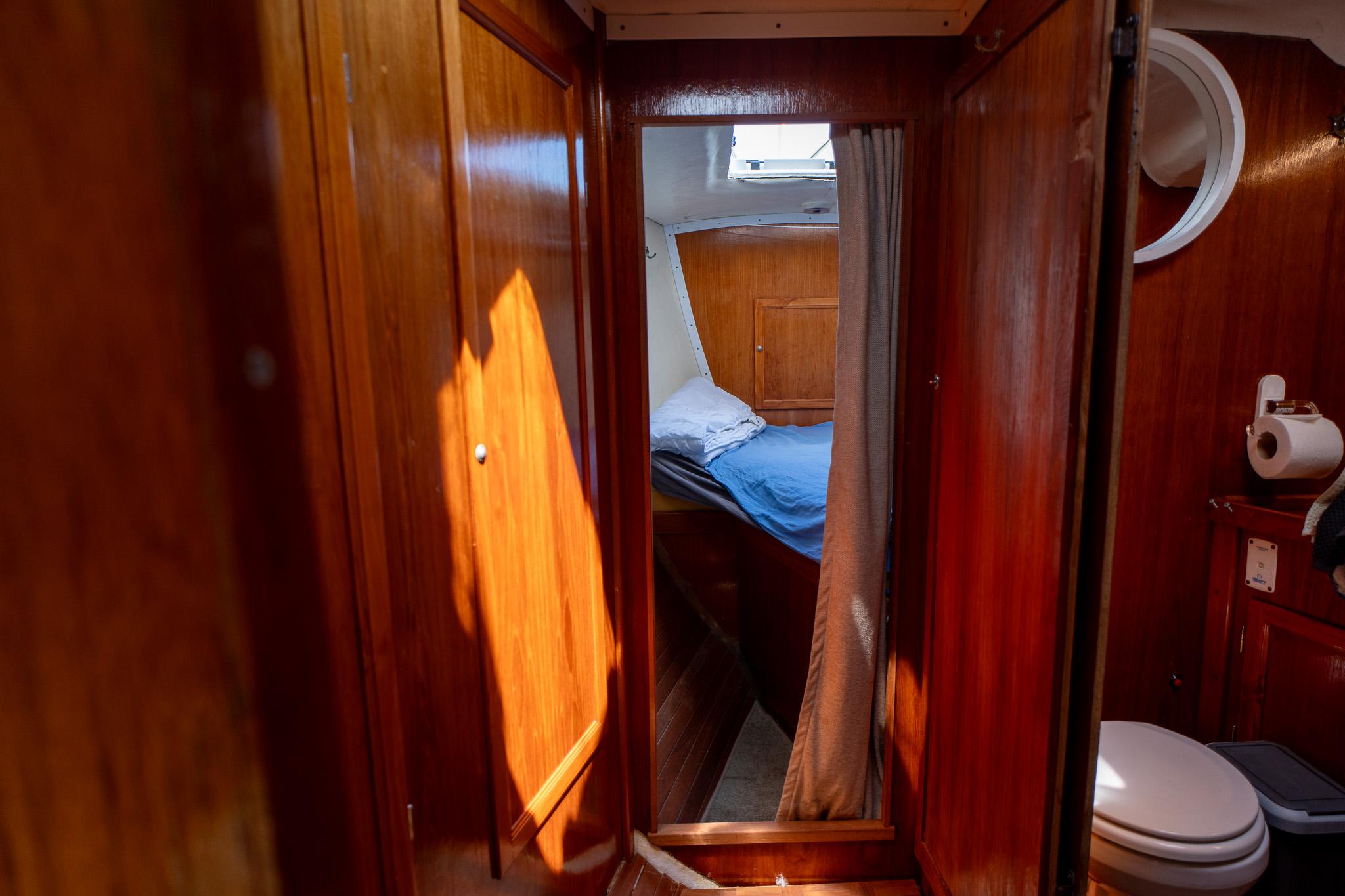 Cozy wooden boat cabin interior with bed and bathroom, Custom 49, 1998 model.
