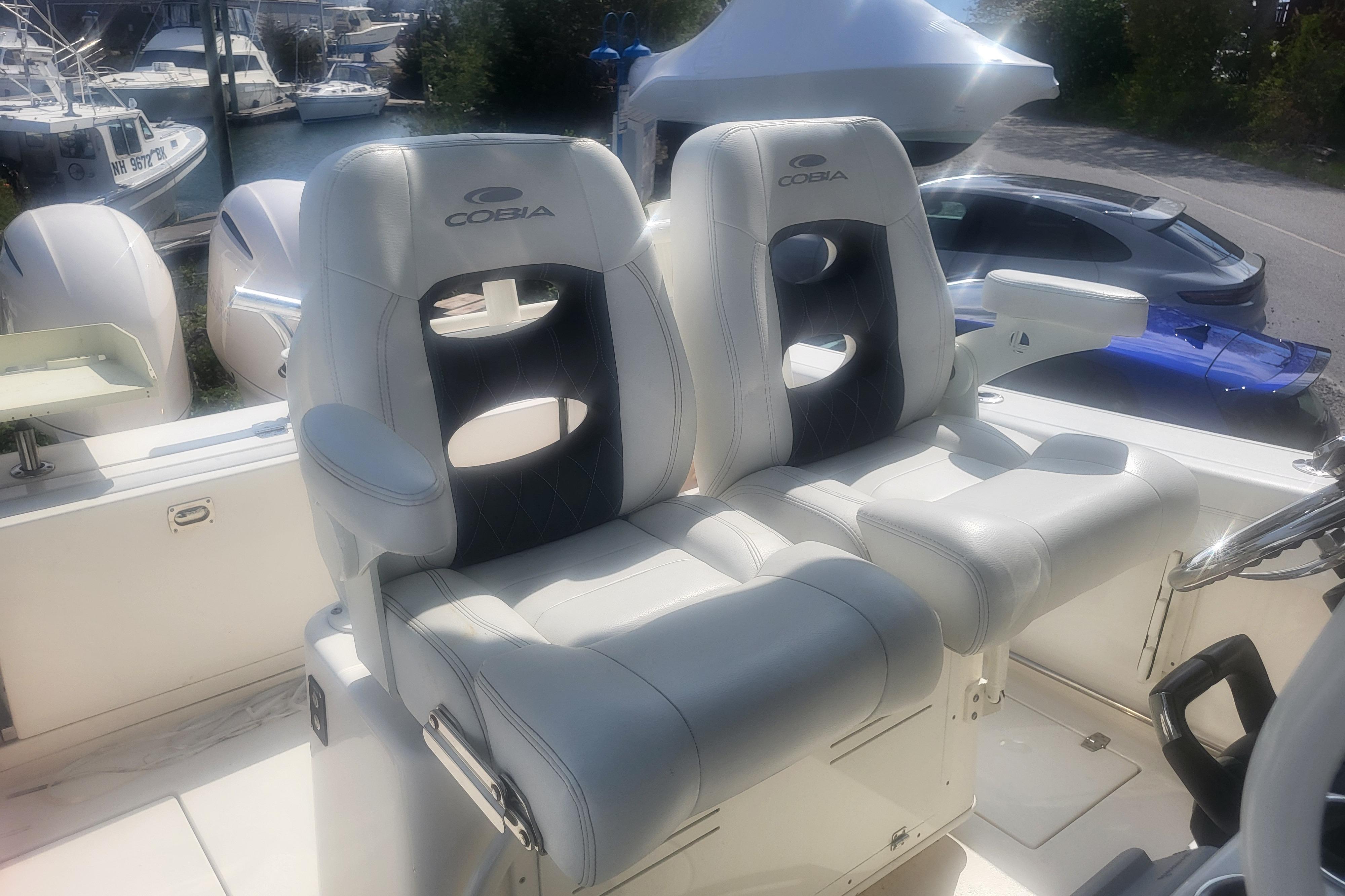 2022 Cobia 262 Center Console boat seats with steering wheel, docked near other boats.