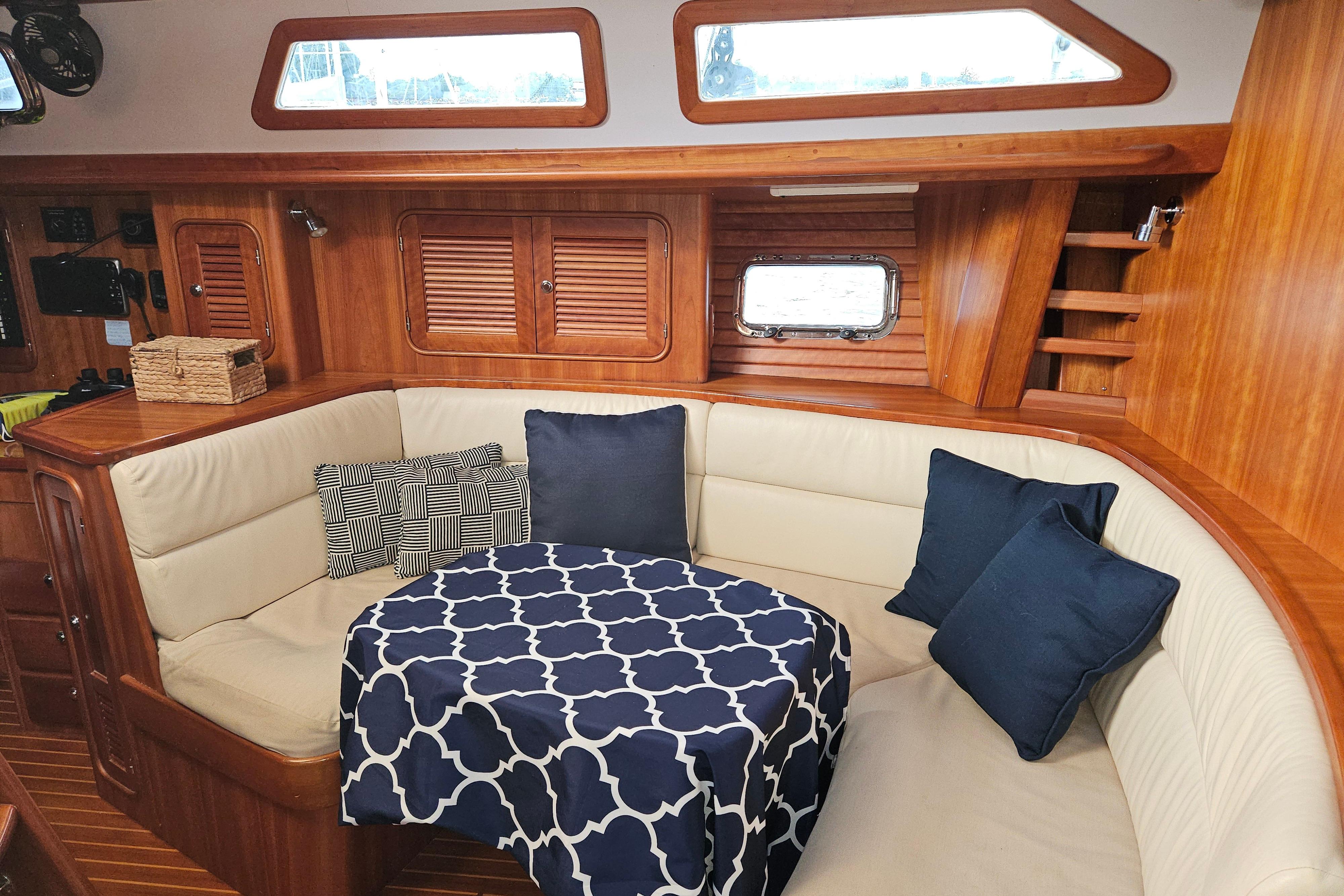 Cozy interior of 2013 Passport 470 Center Cockpit with cushioned seating and nautical decor.