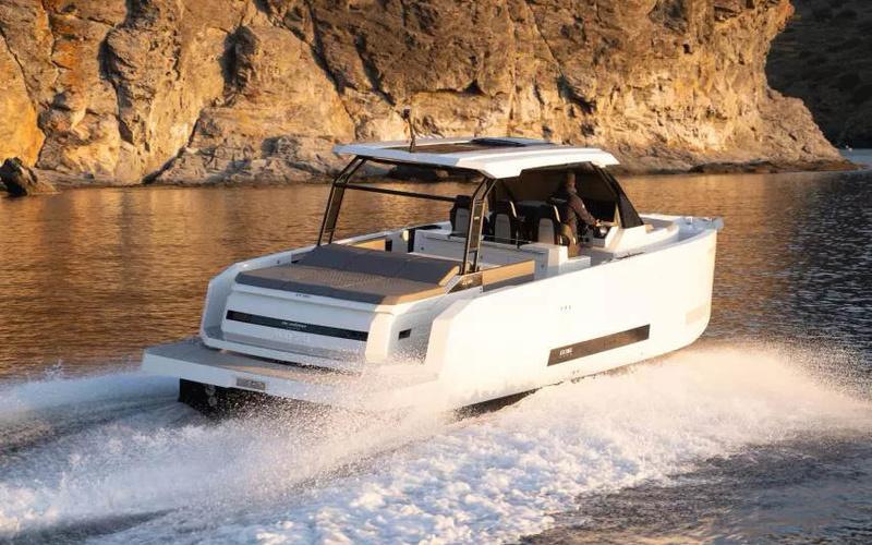 2025 De Antonio Yachts D36 OPEN cruising near rocky coastline at sunset.