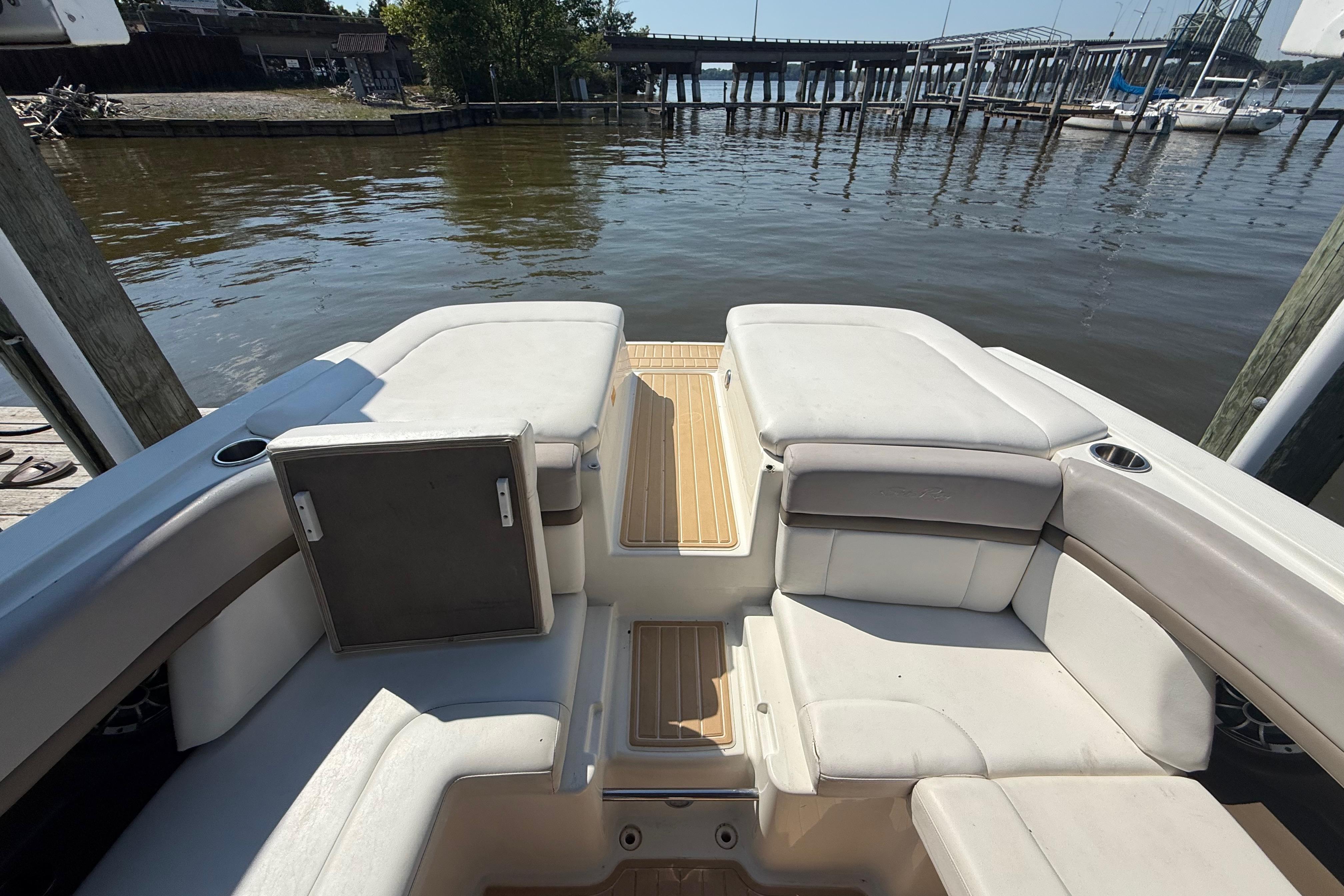 2011 Sea Ray 270 SLX boat interior with white seating, docked by a calm waterfront.