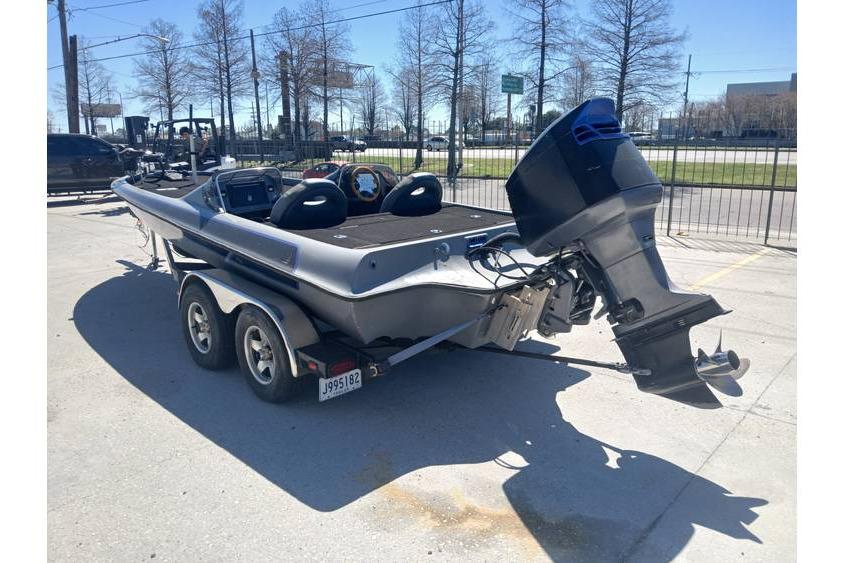 1994 Gambler 21 boat with outboard motor on a trailer in a parking lot.