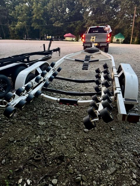 Boat trailer on a gravel lot, ready for transport.