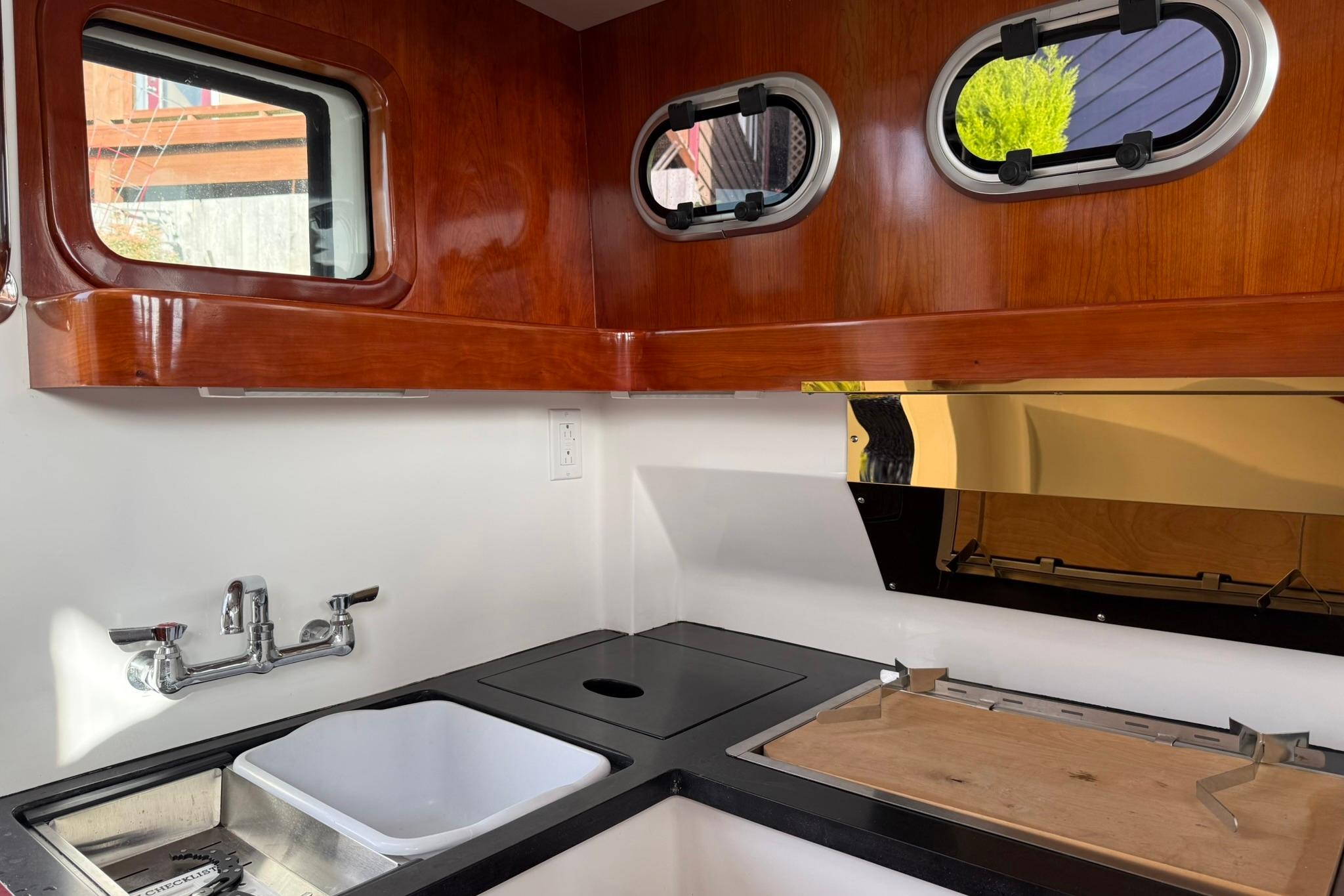 Compact kitchen area in a 2020 SeaPiper 35 boat with wooden cabinetry and stainless steel sink.