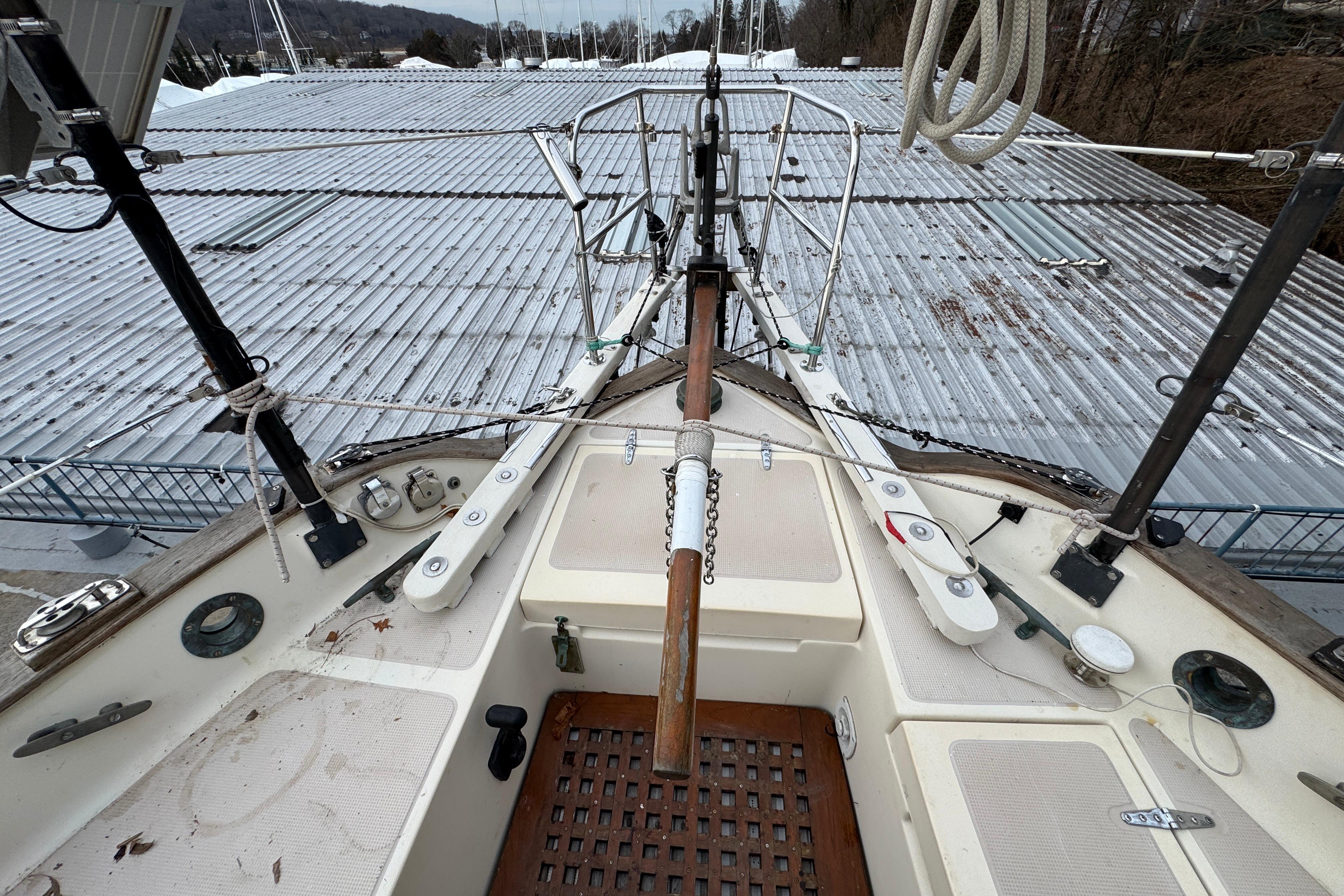 1977 Westsail Cutter sailboat deck with rigging and equipment, docked near metal roofing.