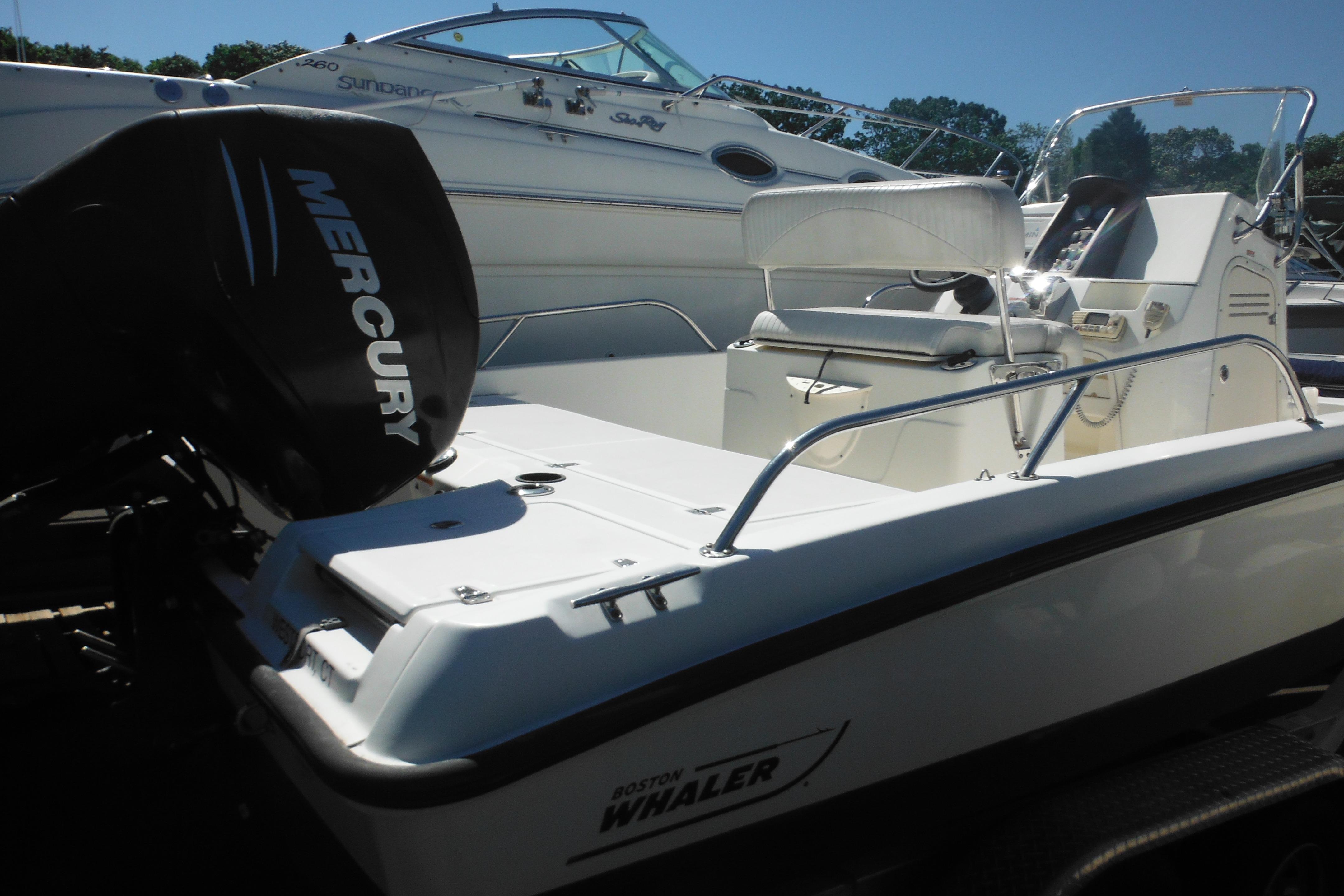 2009 Boston Whaler 200 Dauntless boat with Mercury engine, docked alongside another vessel.