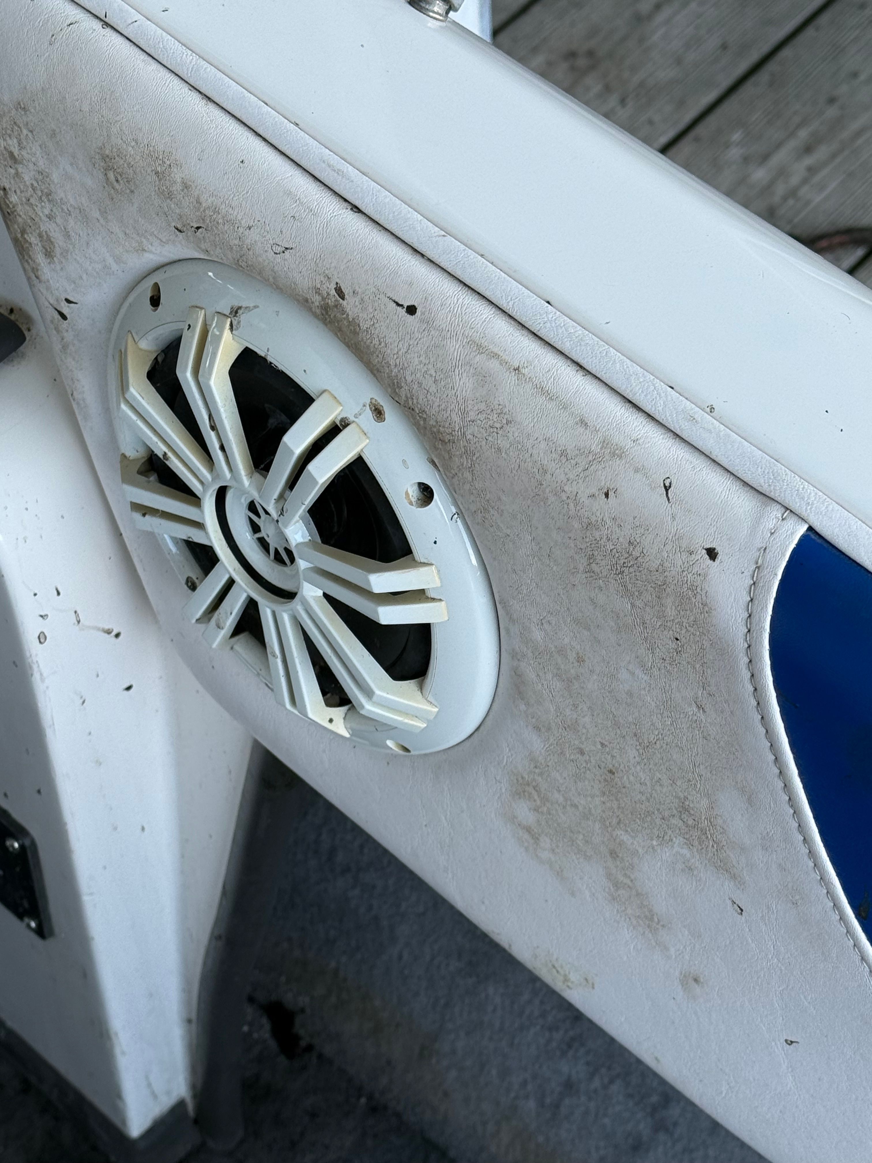 Close-up of a speaker in a boat with worn white upholstery.
