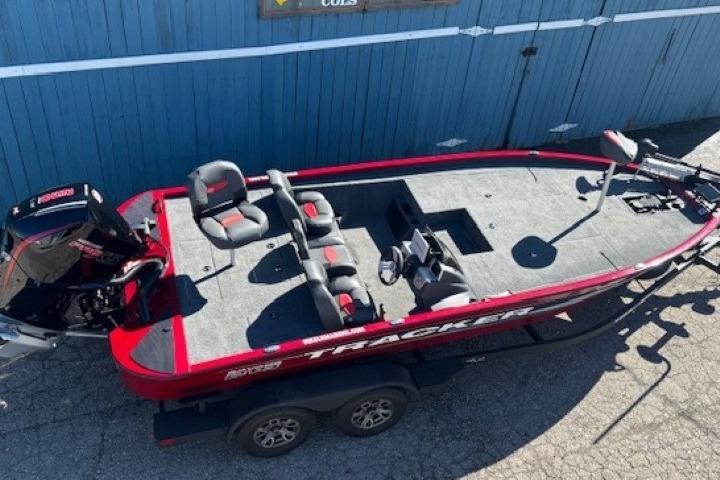 2025 Tracker Savage 215 boat, red and gray, parked on a trailer near a blue wall.