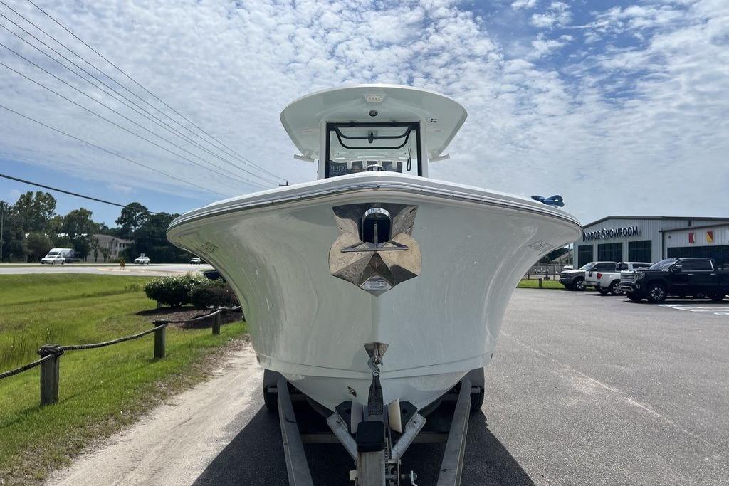 2021 Sea Hunt Gamefish 25 boat on trailer, parked near showroom under cloudy sky.