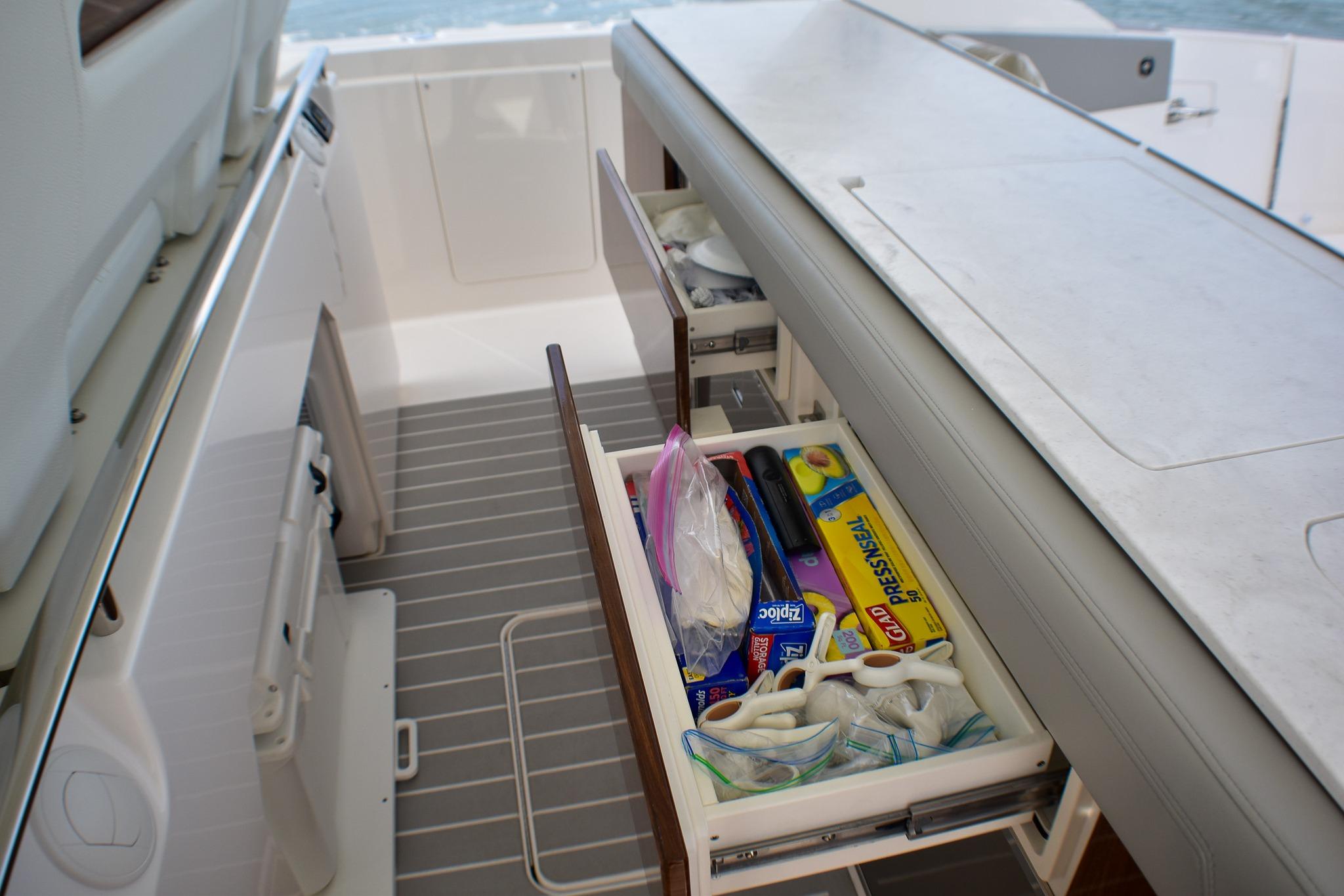 2025 Tiara Yachts 43 LS yacht interior with open storage drawer and kitchen supplies.