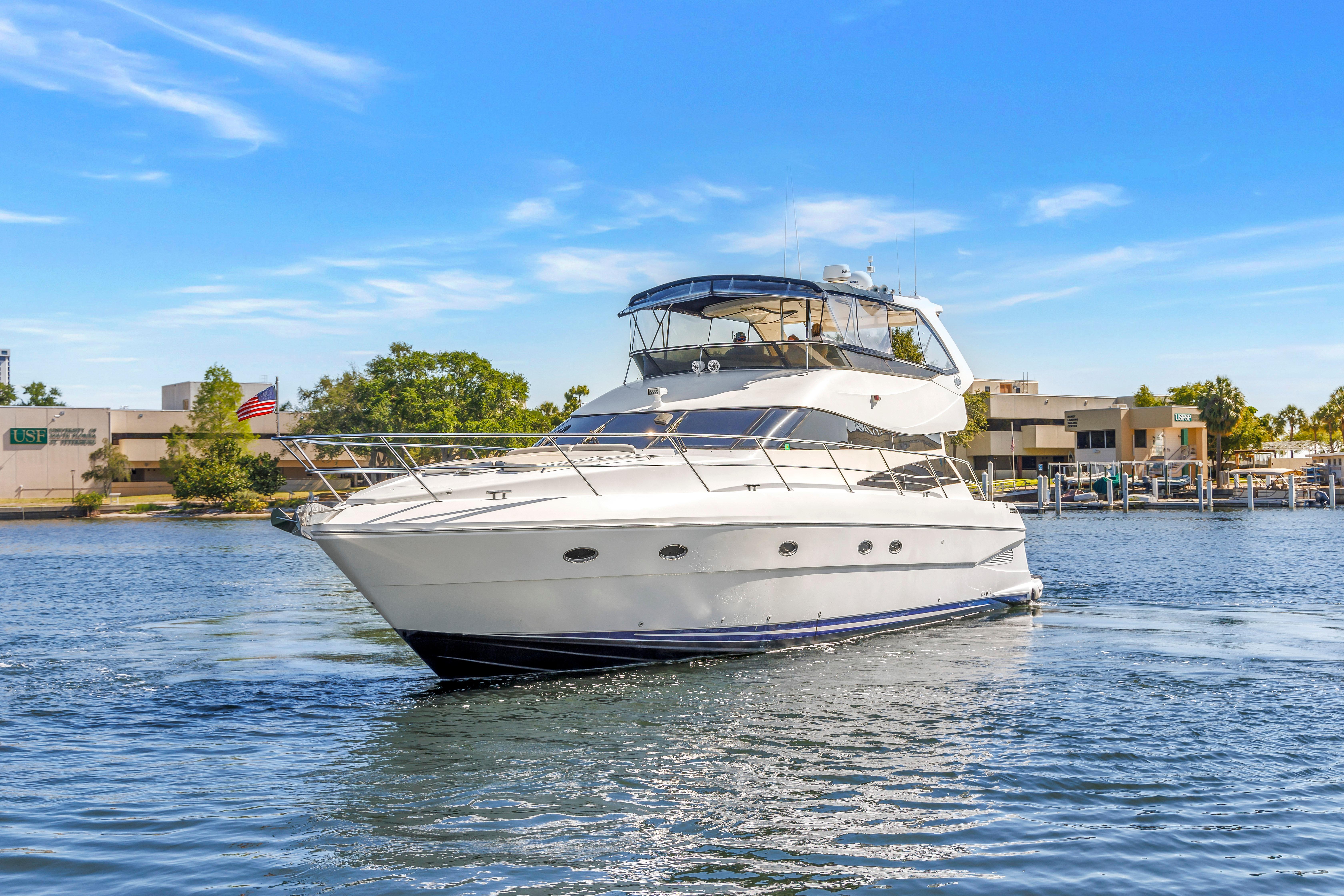 2001 Neptunus 56 Flybridge yacht cruising on a sunny day near a marina.