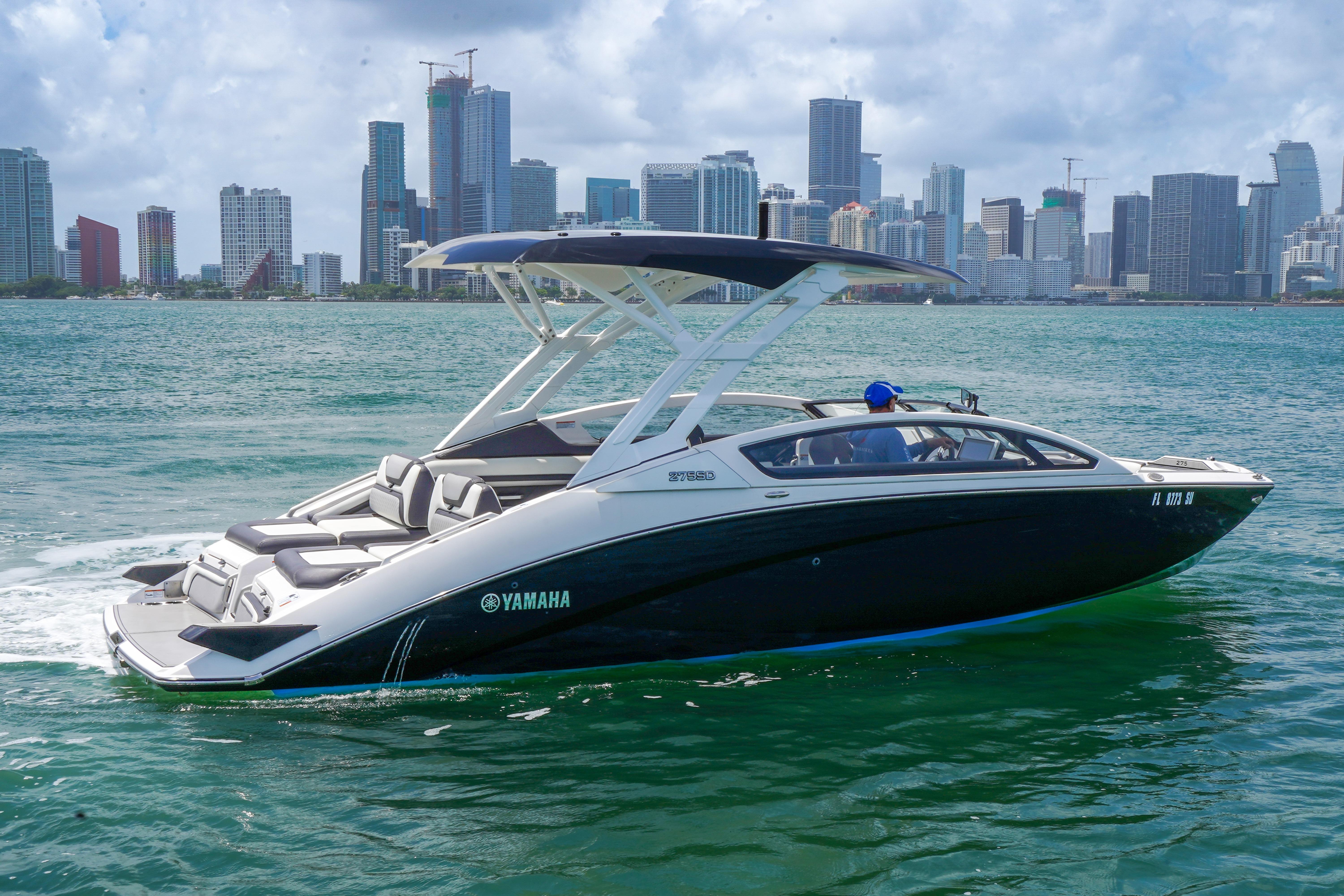 2021 Yamaha Boats 275SD cruising on water with city skyline in background.
