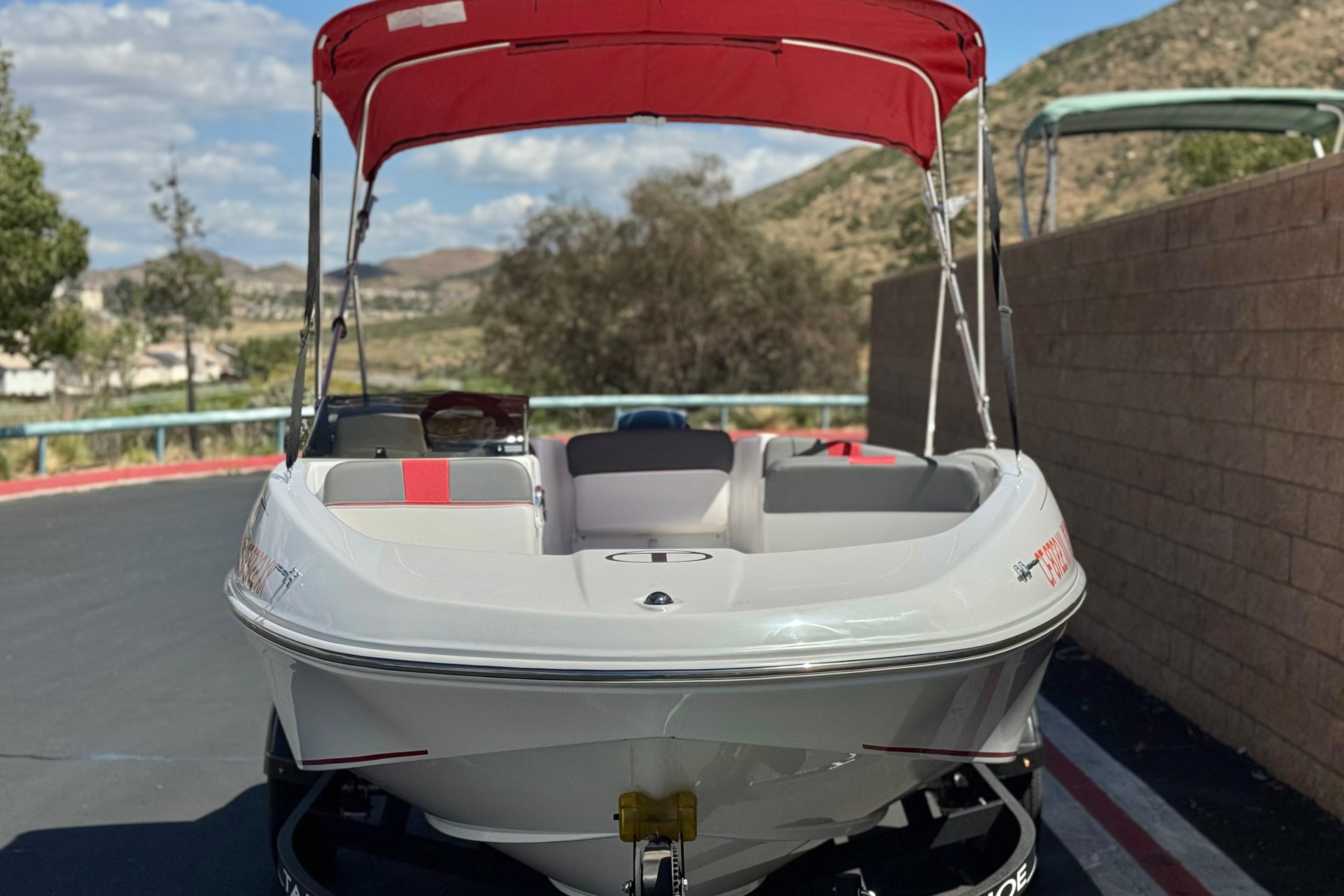 2024 Tahoe T16 boat with red canopy, parked outdoors on a sunny day.