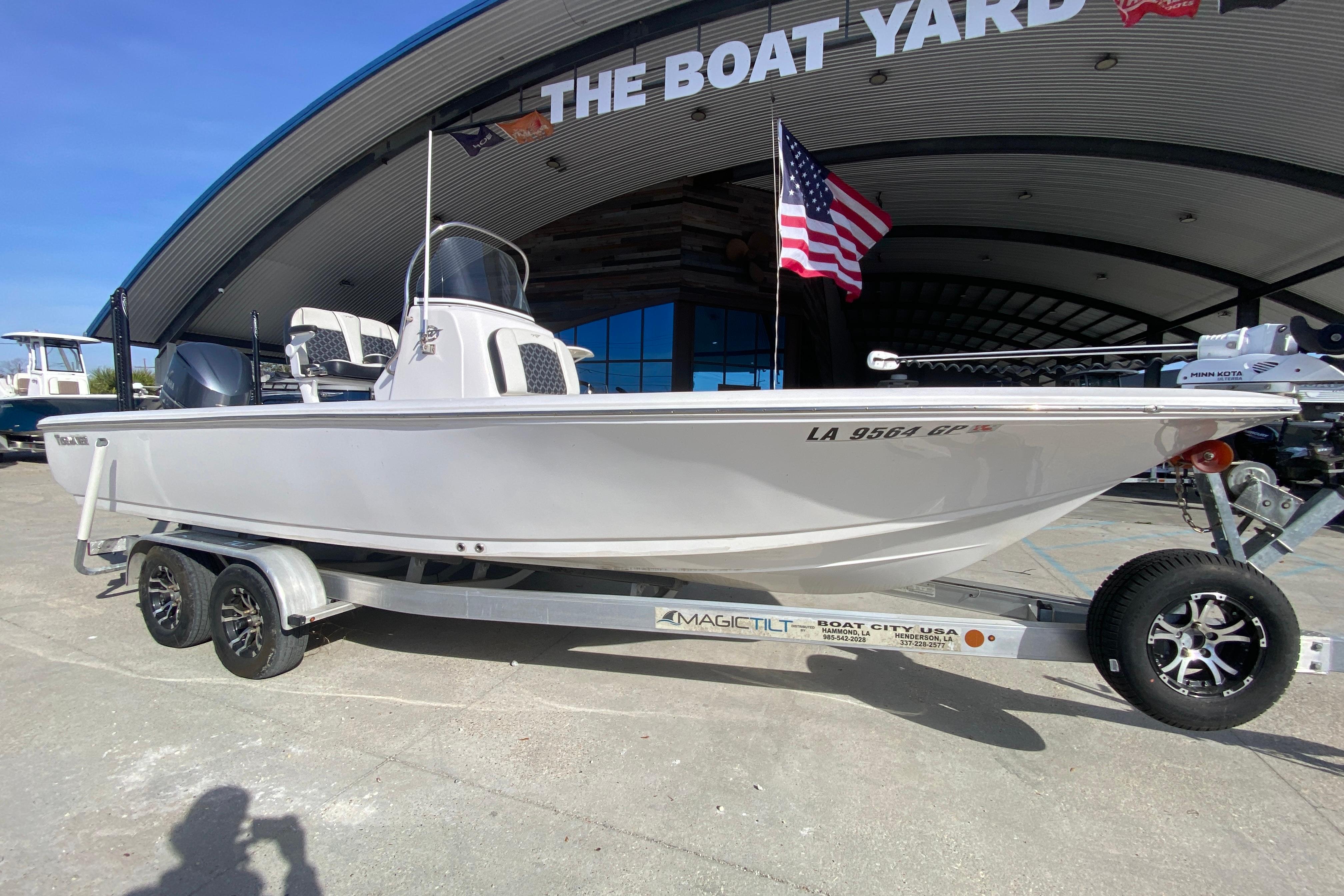 2023 Tidewater 2410 Bay Max boat on trailer at dealership, American flag displayed.