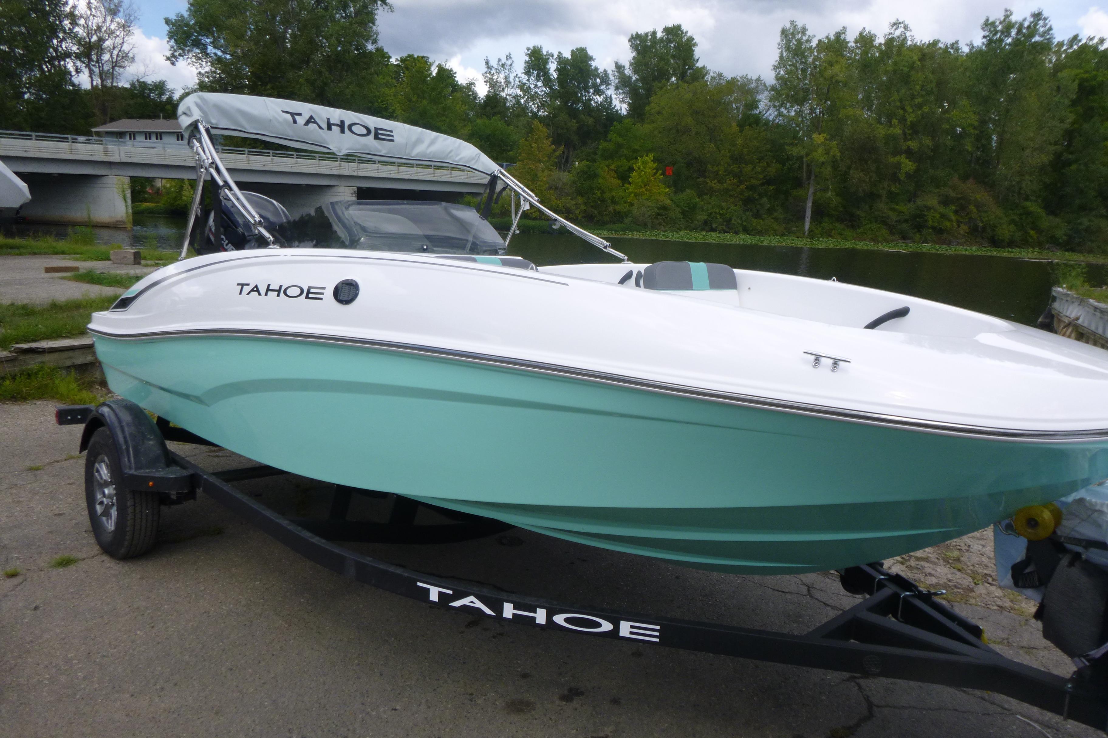 2026 Tahoe T16 boat on trailer by a river, featuring sleek design and mint green hull.