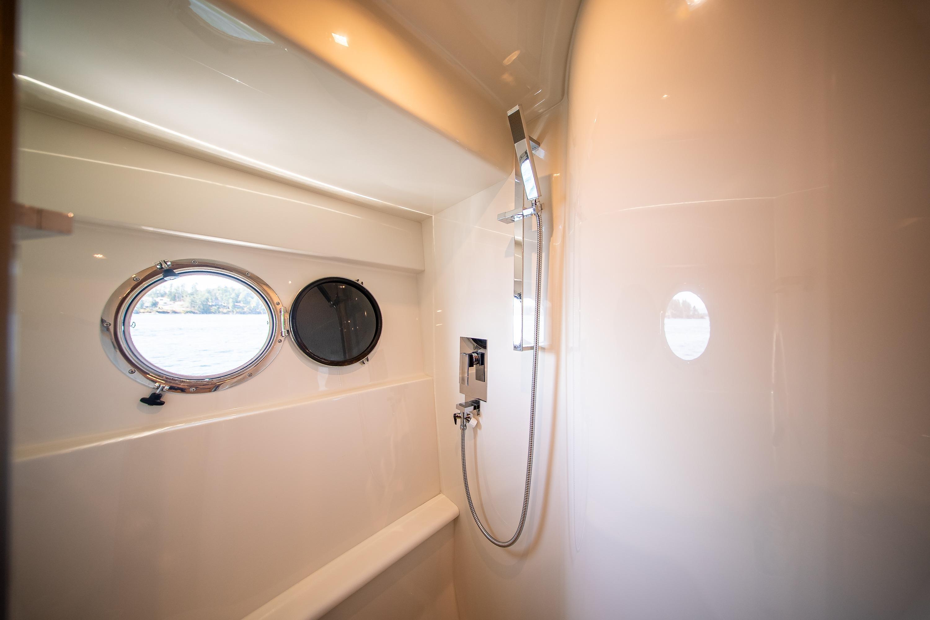 Luxurious bathroom interior of 2012 Marquis 690 yacht with porthole and modern shower.