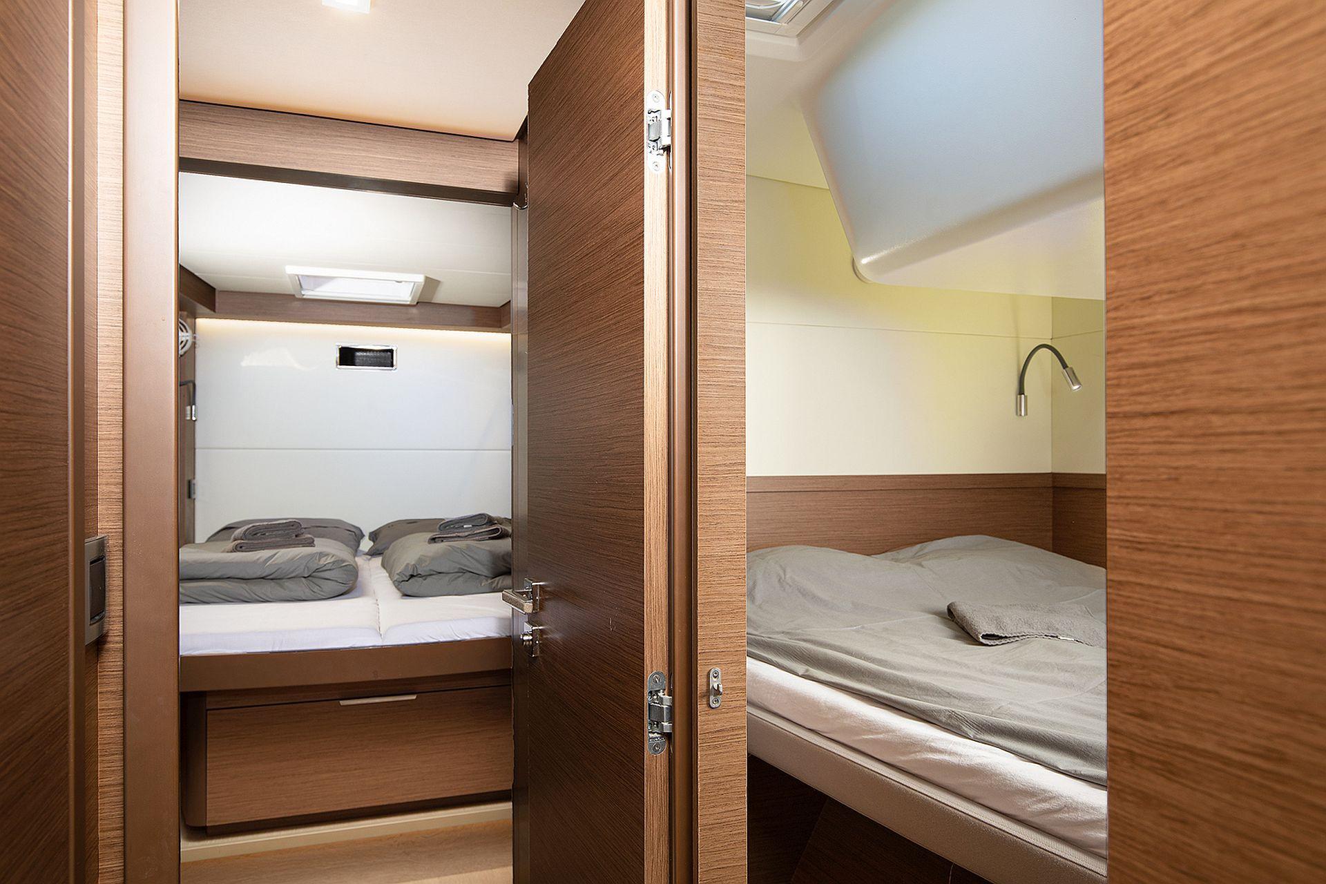 Interior of 2022 Lagoon 500 yacht, featuring cozy twin cabins with modern wood finish.