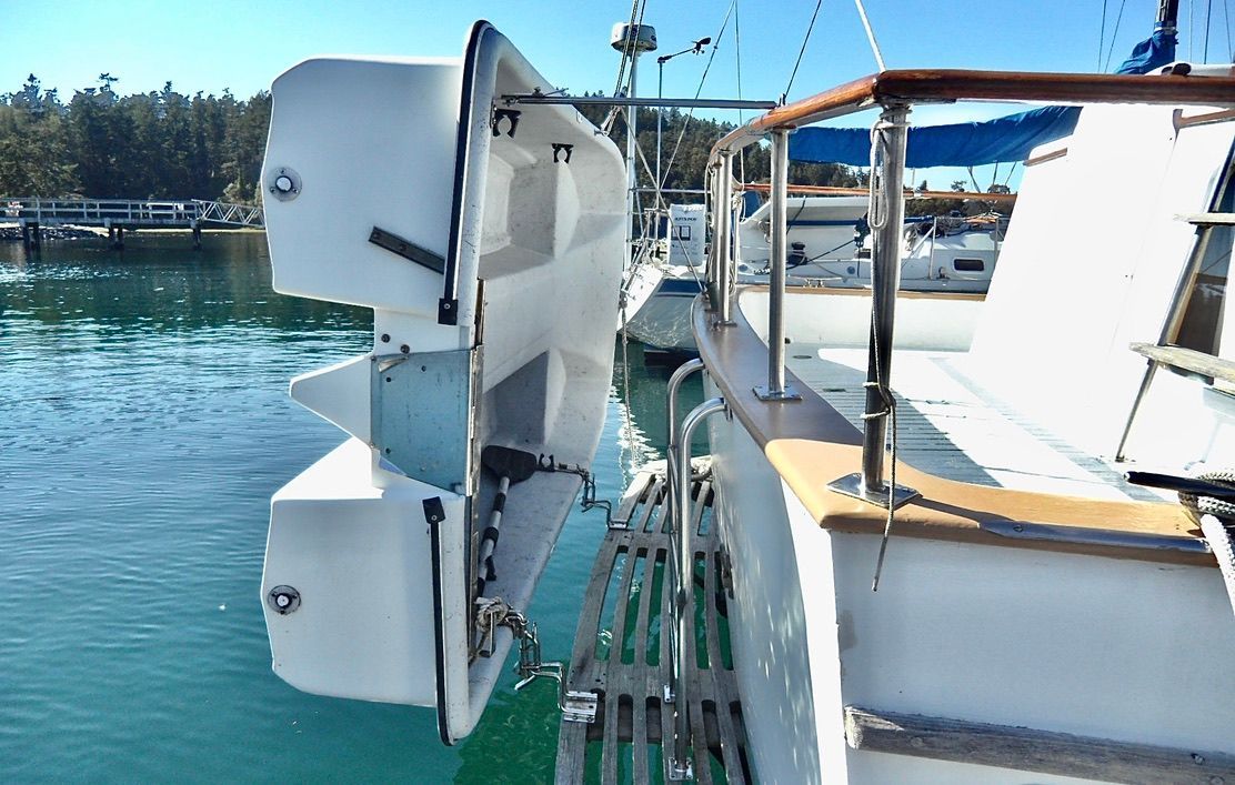 1976 CHB Trawler with dinghy on davits, docked in a serene marina.