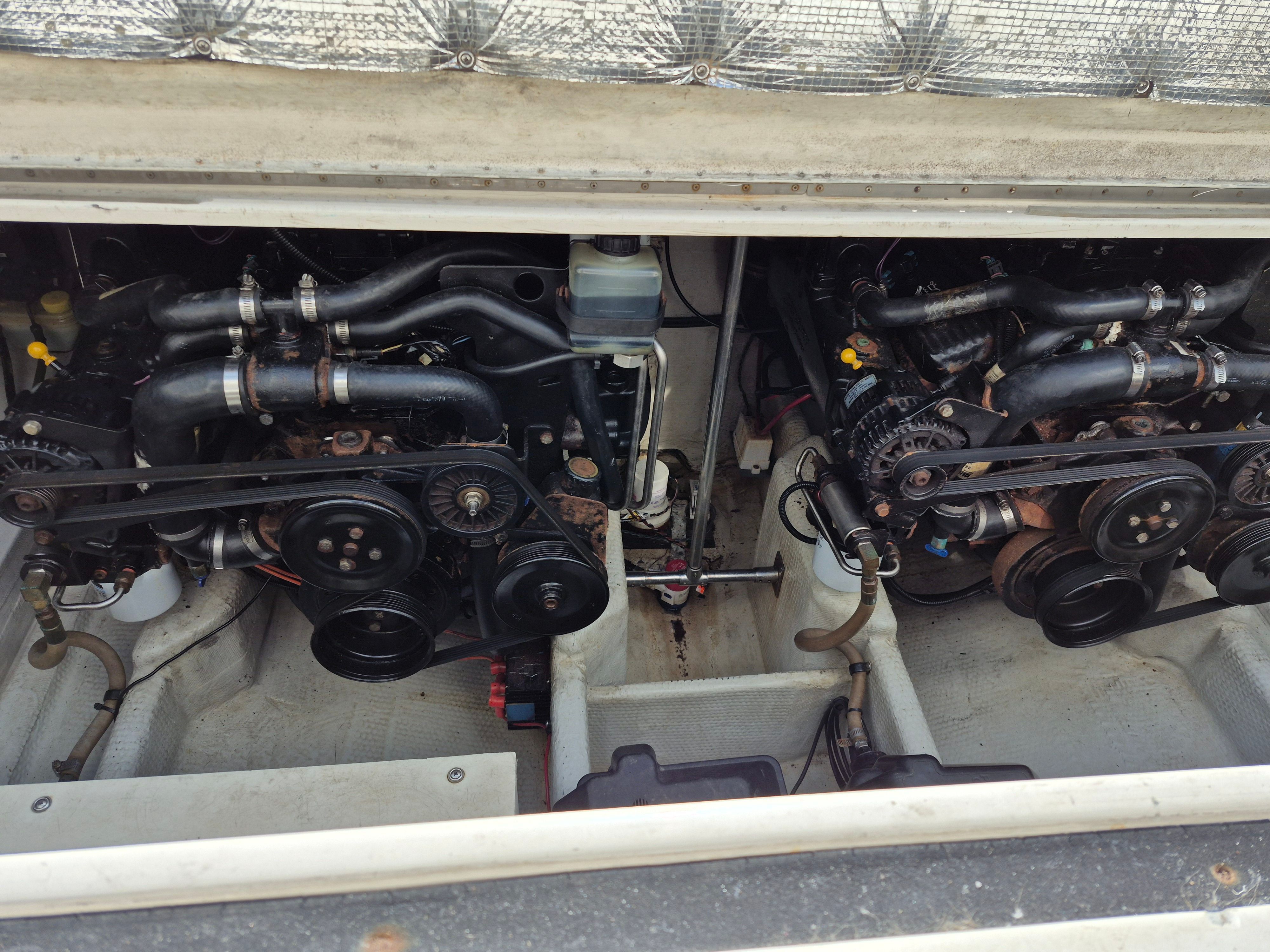 Two engines in a boat's engine compartment, with visible belts and pipes.