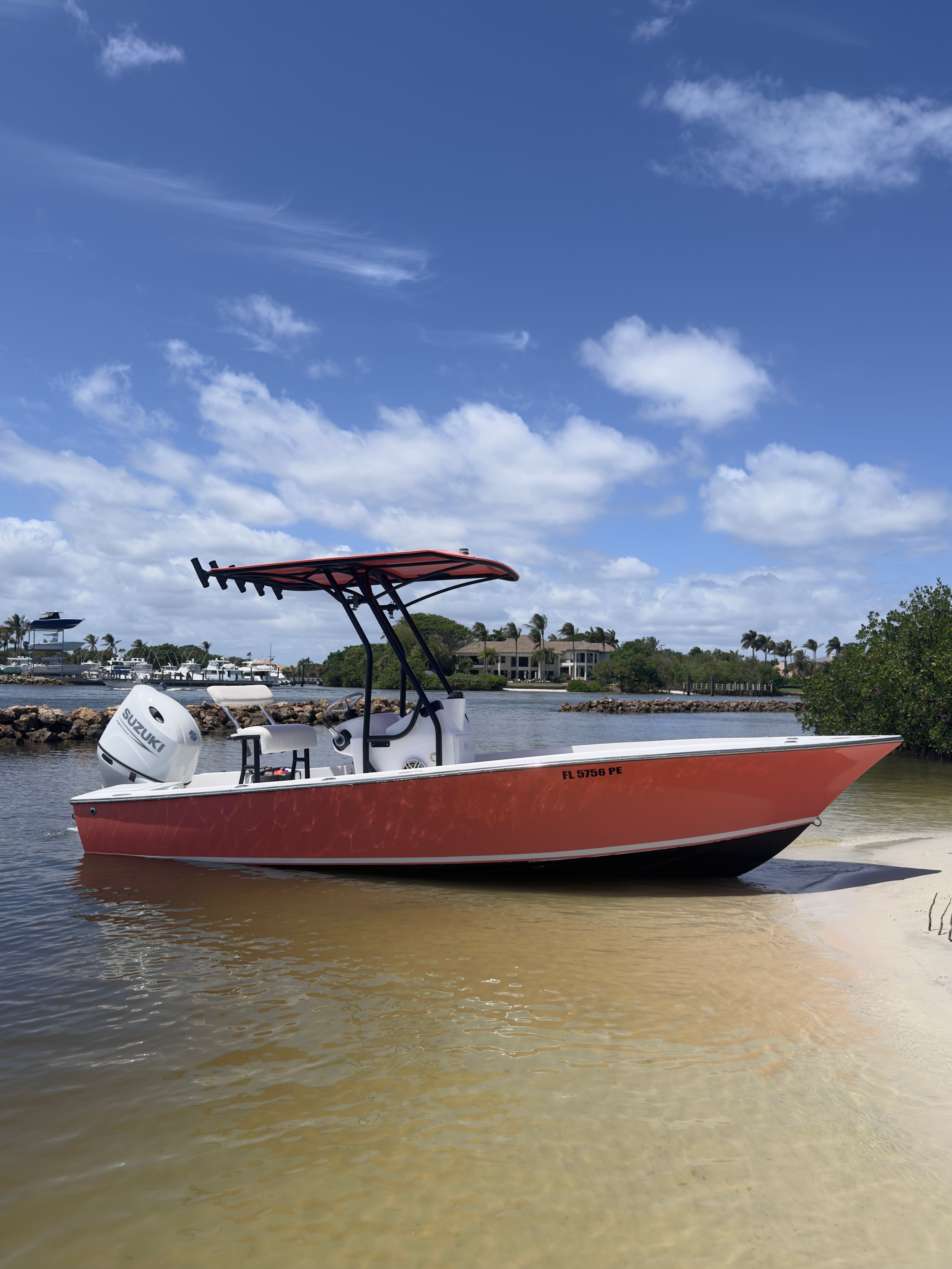 A red boat with a canopy is docked on a sandy riverbank.