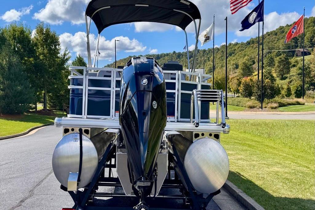 2026 Sun Tracker Sportfish 24 XP3 pontoon boat with flags and scenic background.