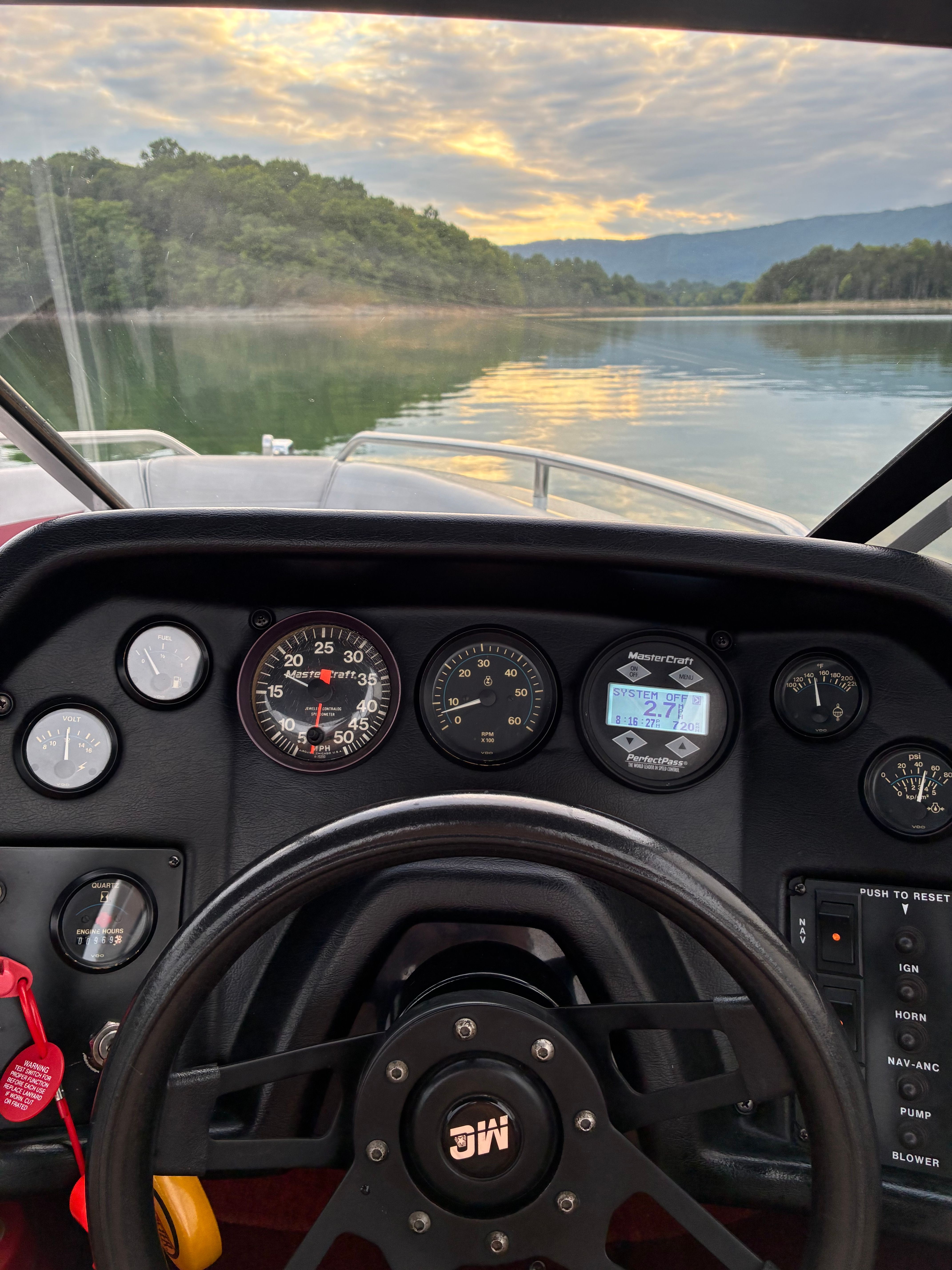 The dashboard of a 1989 MasterCraft TriStar 190 overlooking a calm lake.