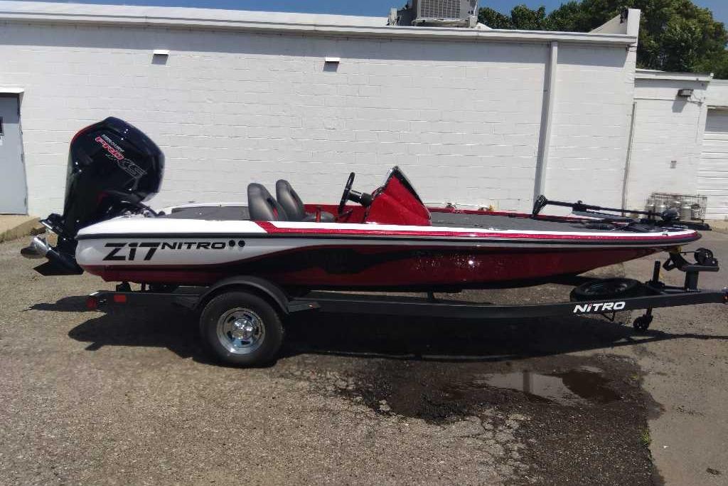 2026 Nitro Z17 boat with trailer, parked outdoors, featuring sleek red and white design.