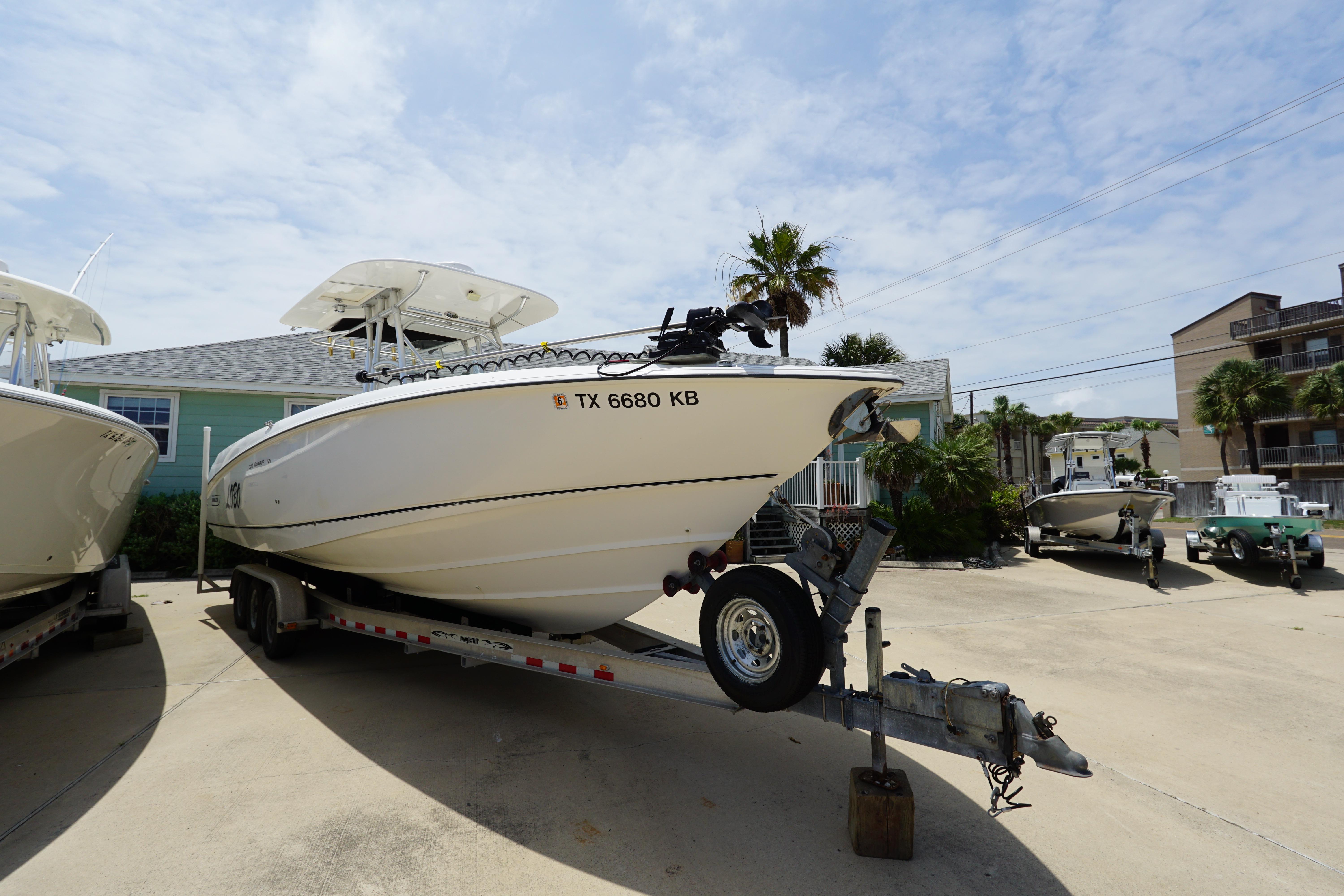 2004 Boston Whaler 320 Outrage boat on trailer, parked outdoors under a clear sky.