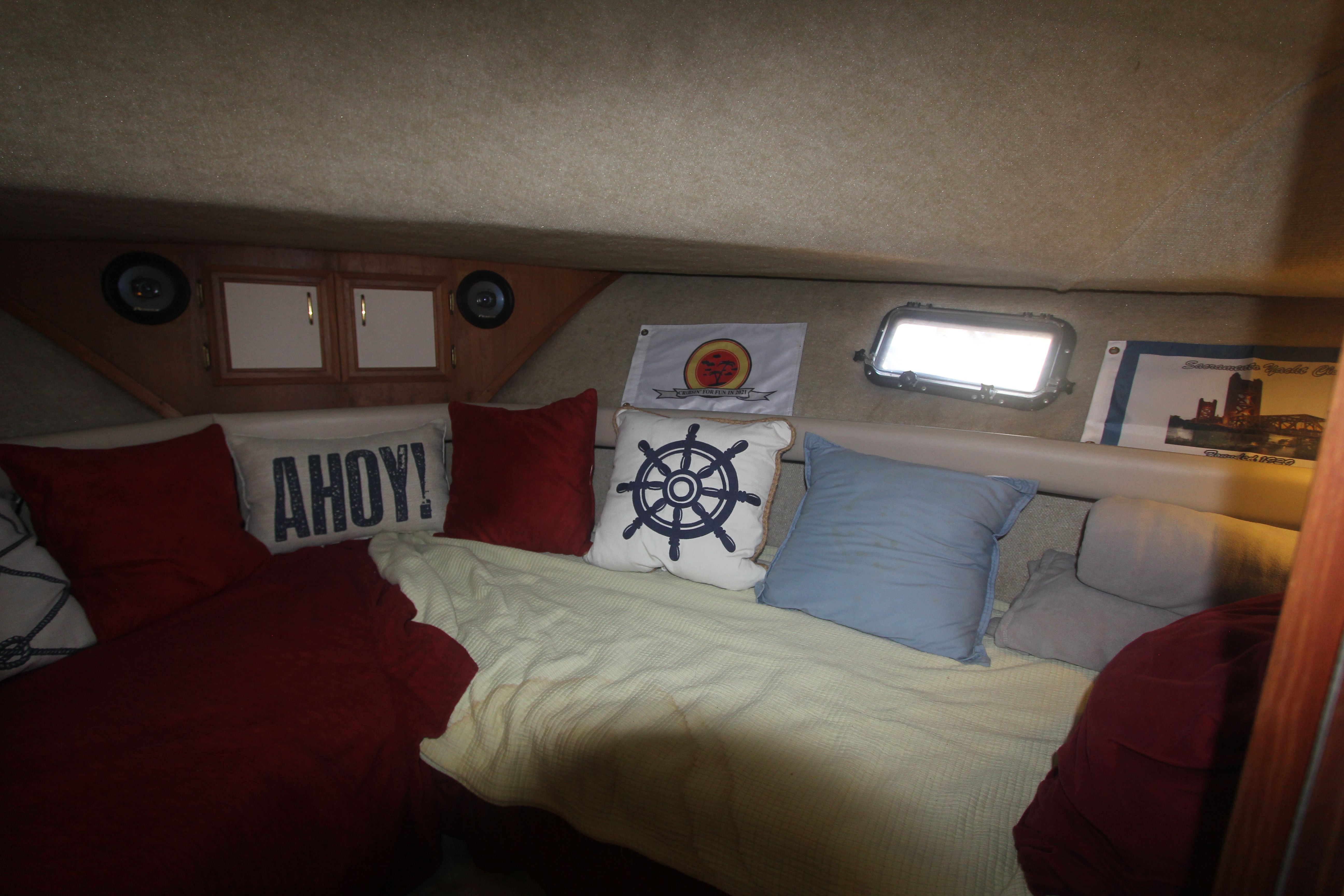 Cozy cabin with cushions, porthole, and wooden cabinetry.