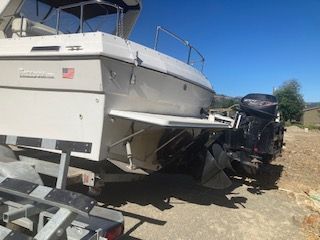 A white boat is on a trailer on dry land.