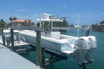 2002 Intrepid 323 Cuddy boat docked with dual outboard engines in a sunny marina.
