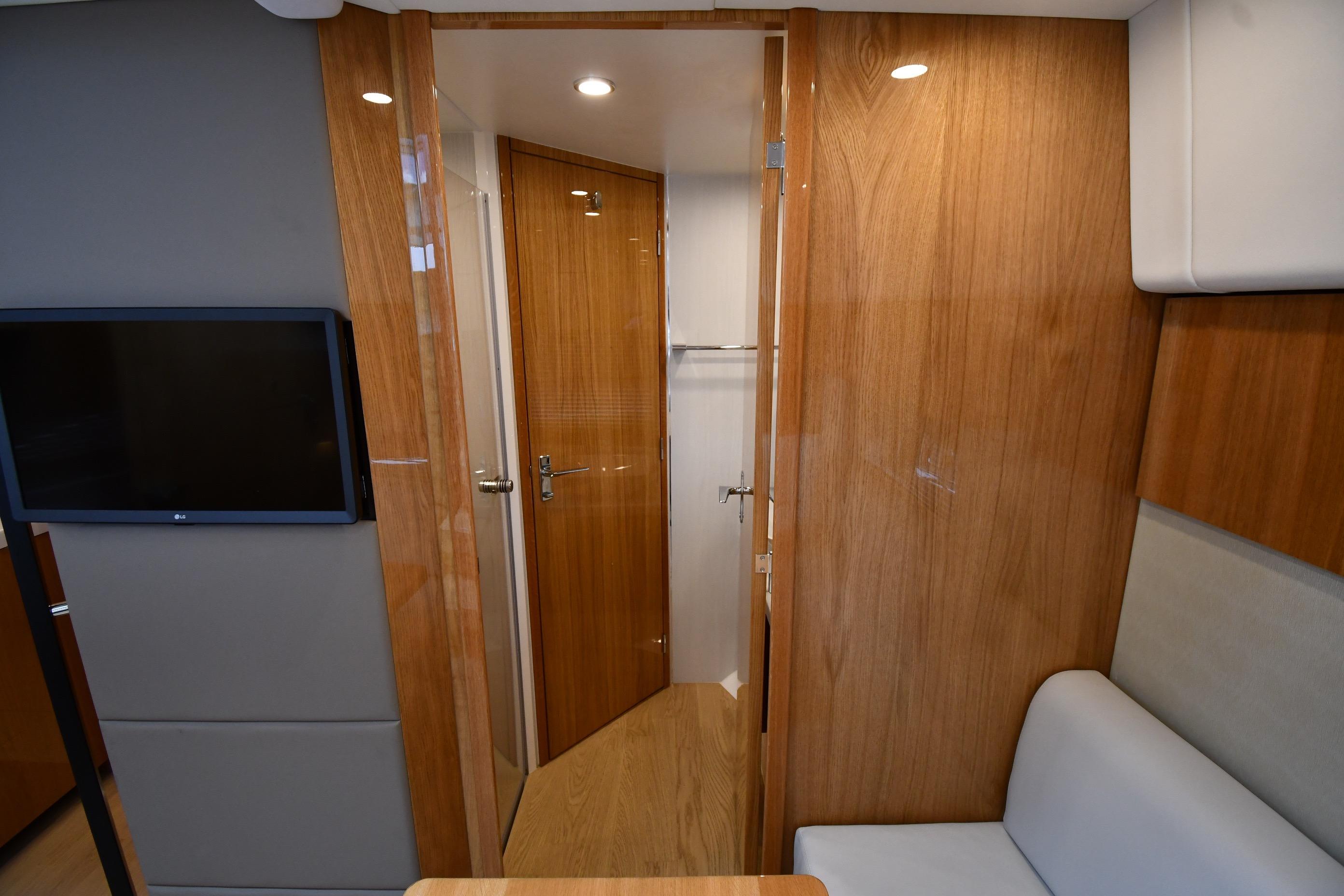 Interior of 2024 Fairline G50 Targa yacht with wooden finishes and a mounted TV.