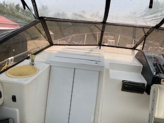 The cockpit of a boat with a steering console and a sink.