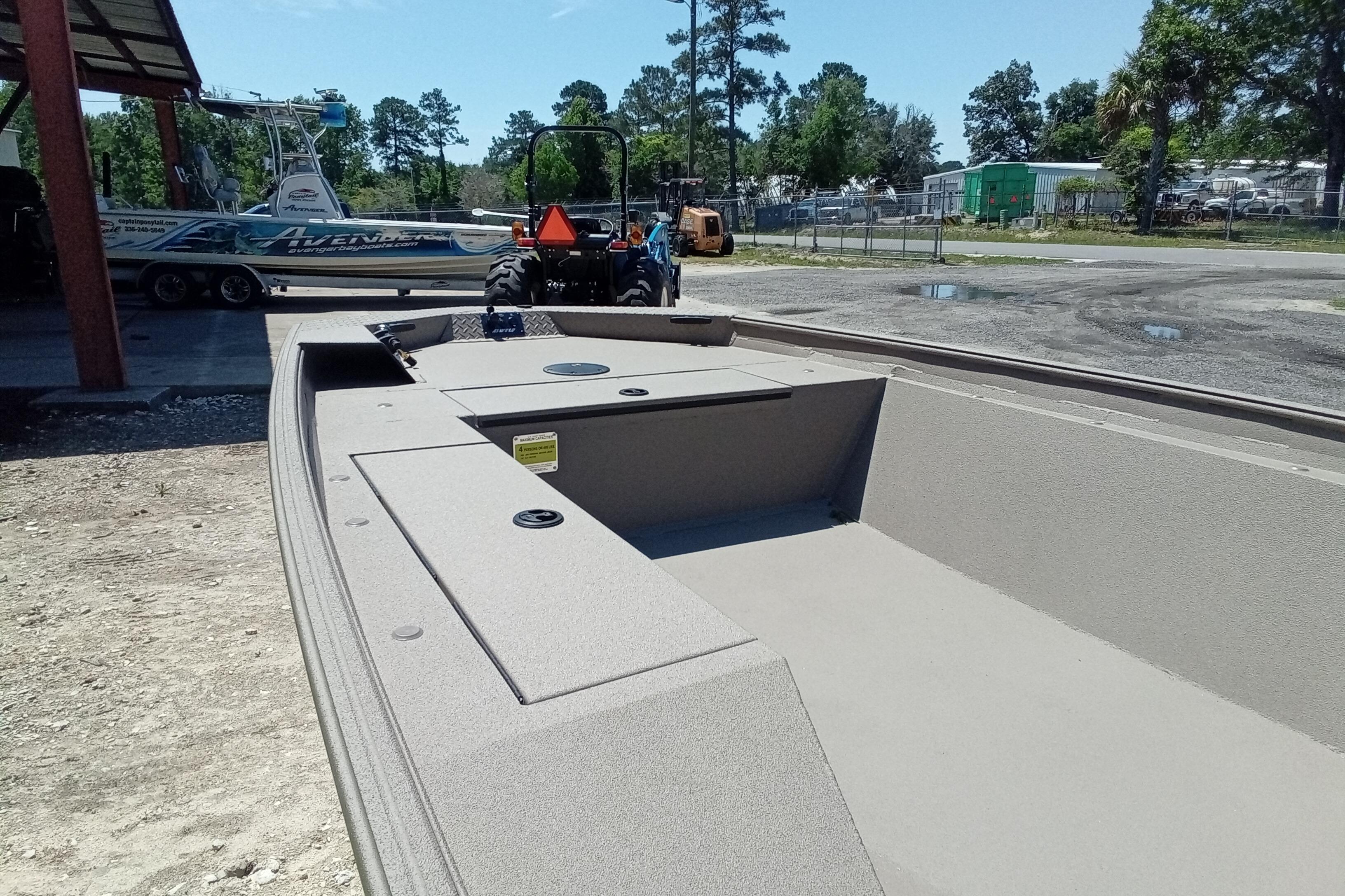 2026 Alweld 1652 Invader boat interior, parked outdoors with trees and equipment nearby.