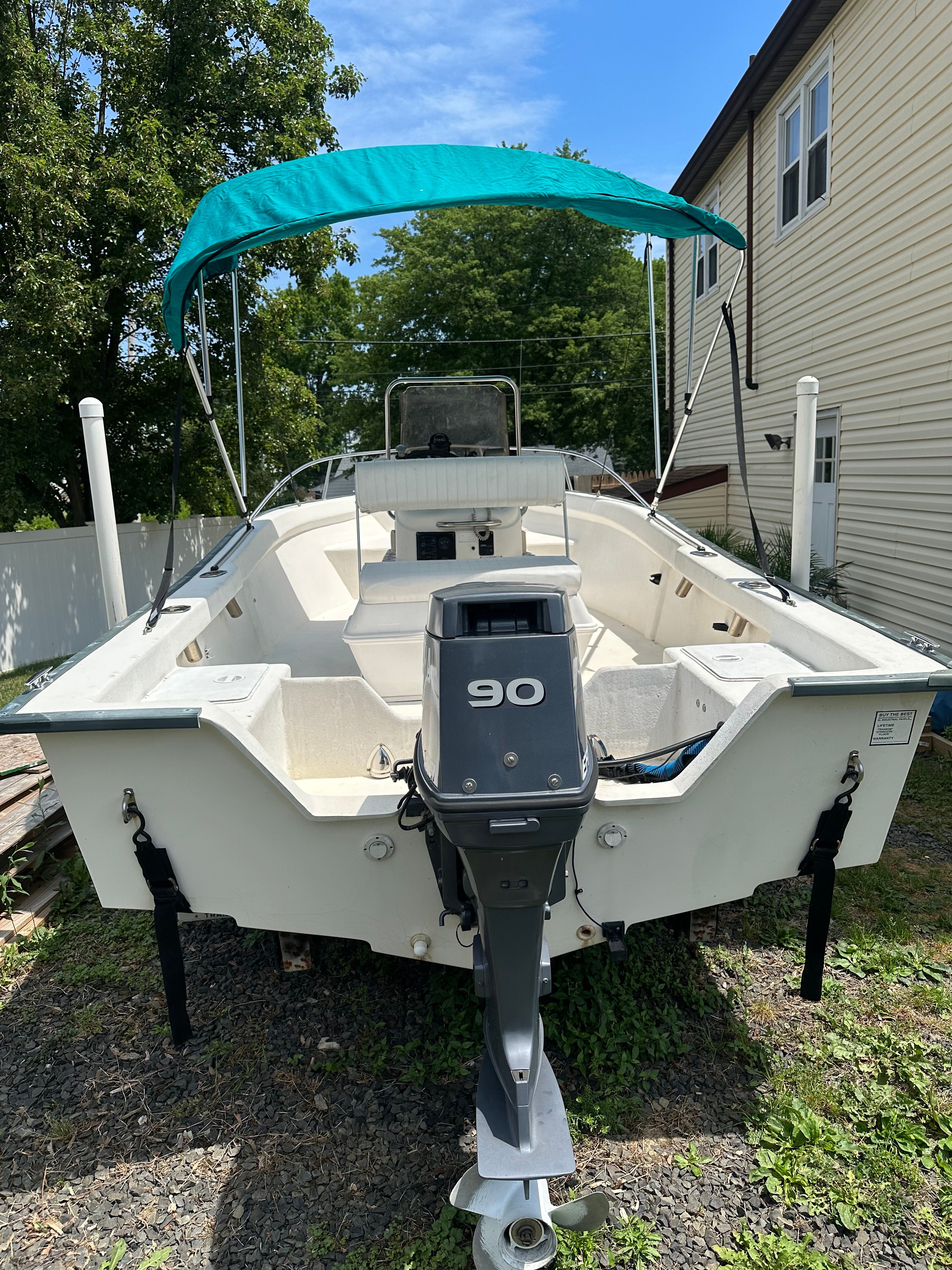 A 2003 Key Largo 180 Center Console boat with a 90 HP outboard motor and blue sunshade.